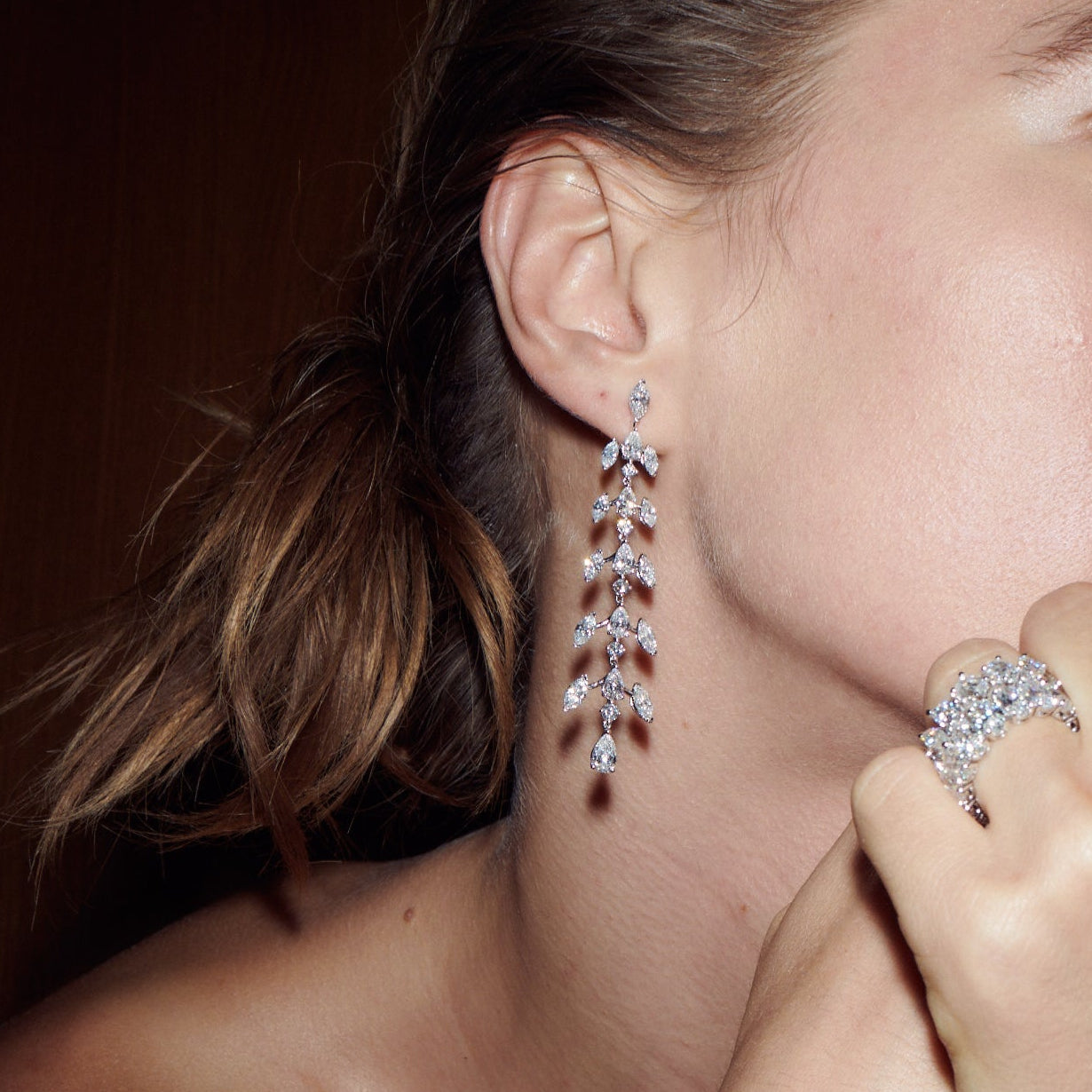 Model wearing The Sirène Earrings in 18K white gold, with elongated rows of marquise, pear, and round diamonds falling from the ear.