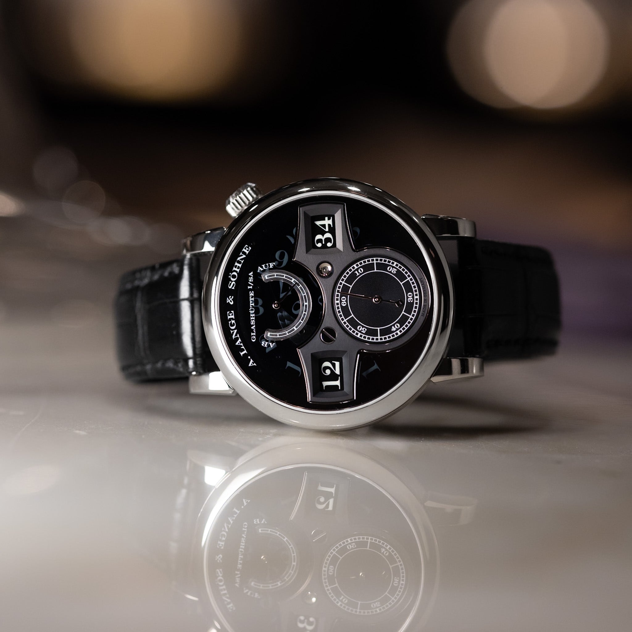 Black wristwatch with detailed face on a reflective surface