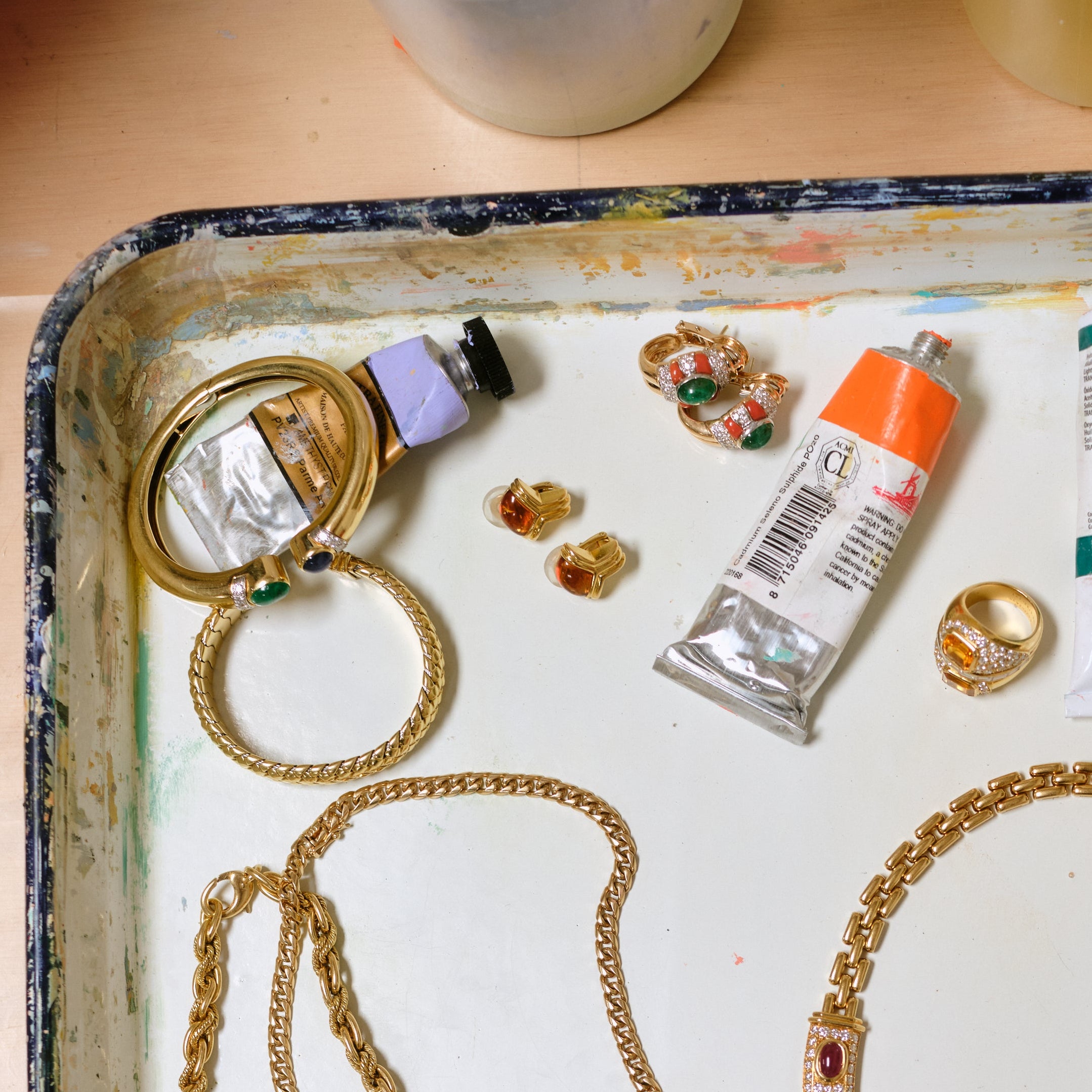 Vintage Bvlgari citrine huggie earrings resting on a paint-splattered tray alongside other gold vintage jewelry