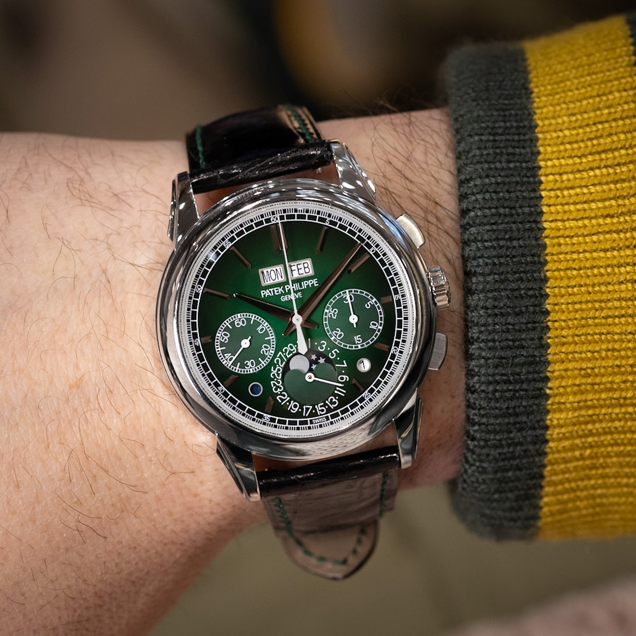 Close-up of a wrist wearing a detailed wristwatch with a green face.