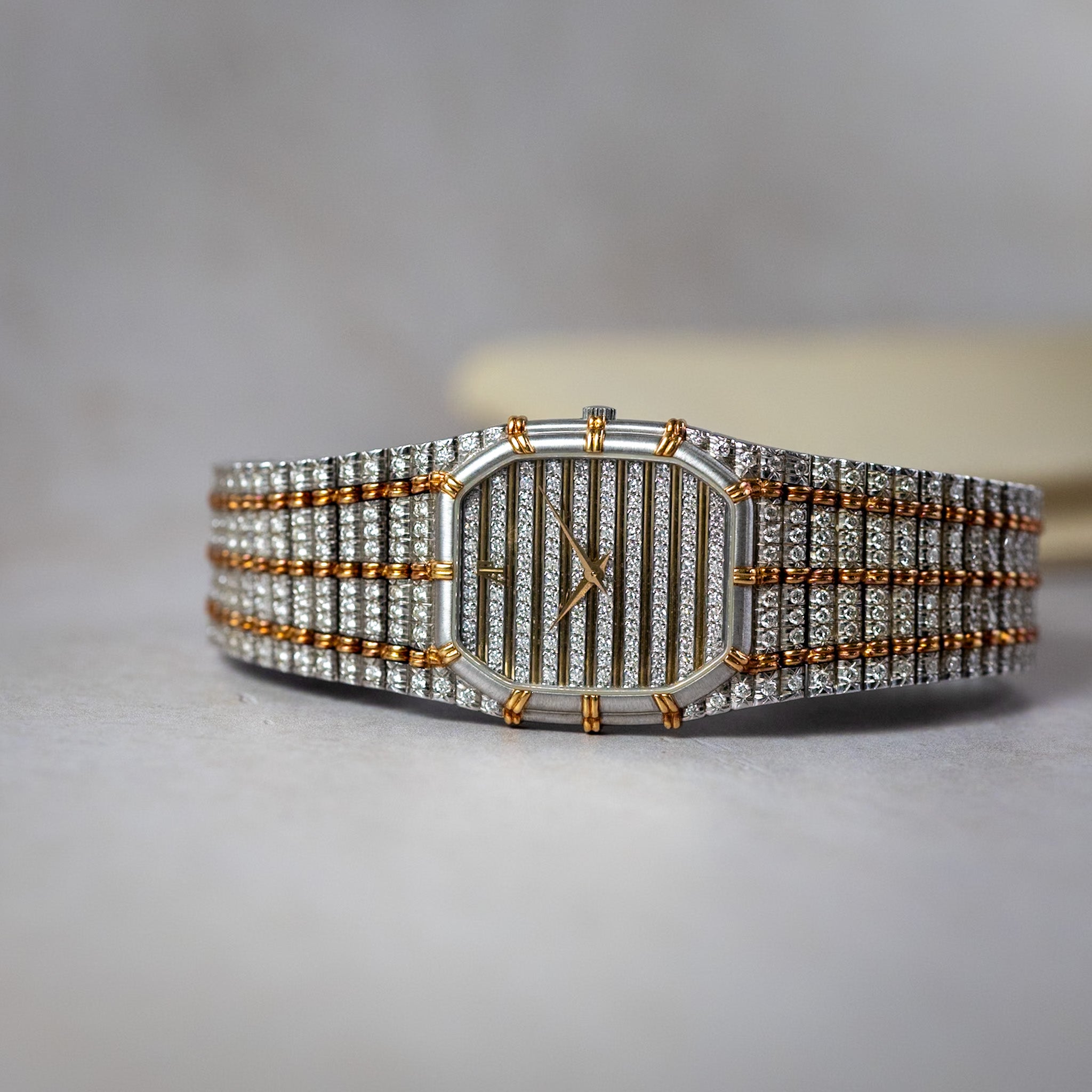 Luxury watch with diamond-studded band on a neutral background