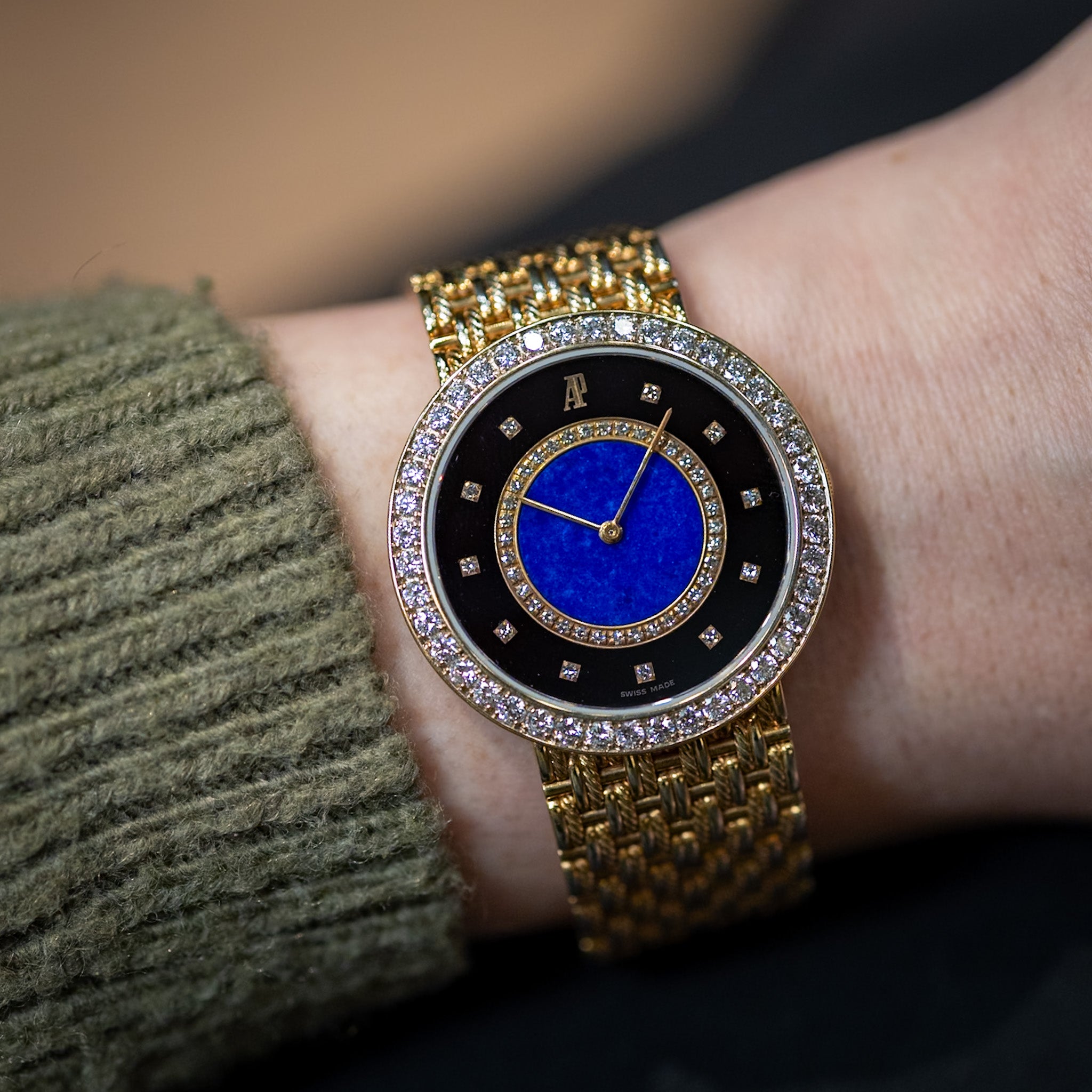 Gold watch with a blue face on a wrist, worn by a person.