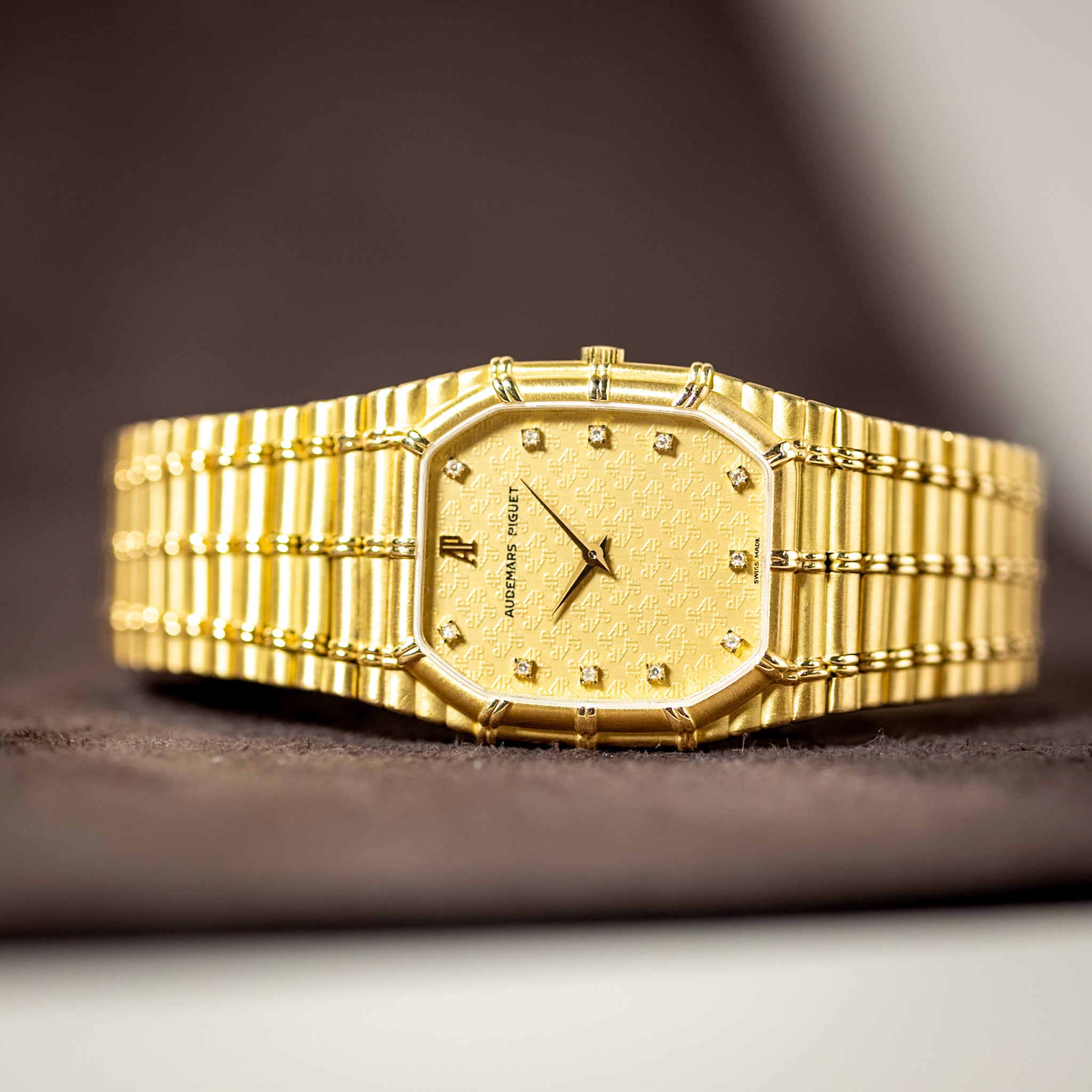Gold wristwatch with a textured band on a dark surface