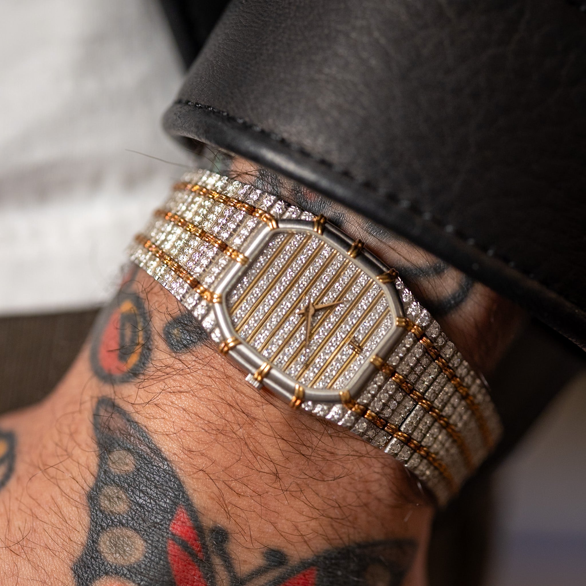 Gold and silver watch on a wrist with tattoos