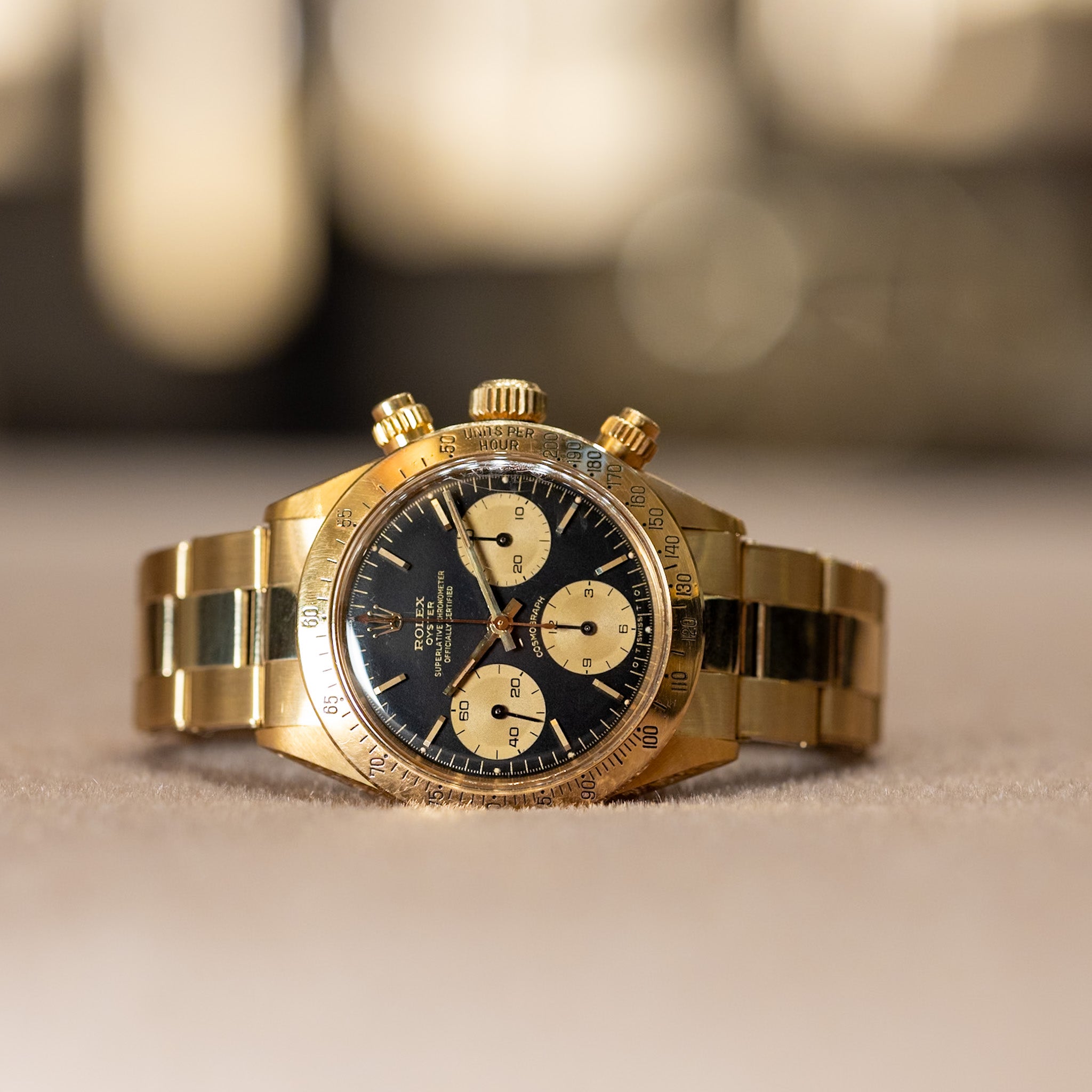 Gold wristwatch with a black face on a blurred background