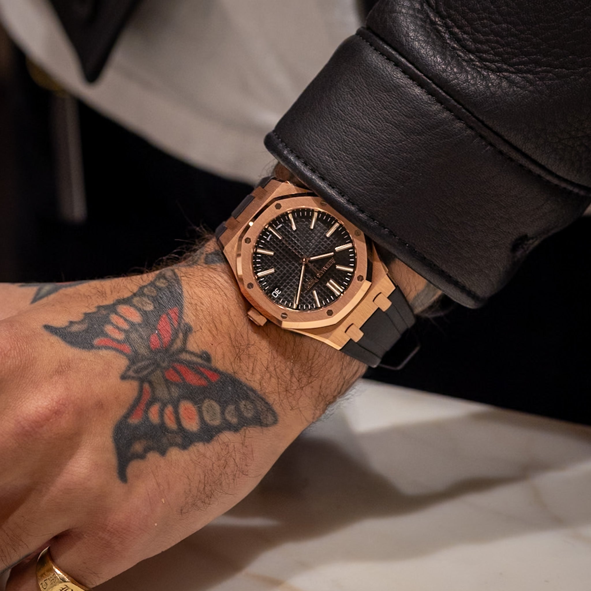 Luxury watch on a wrist with a tattoo of a butterfly