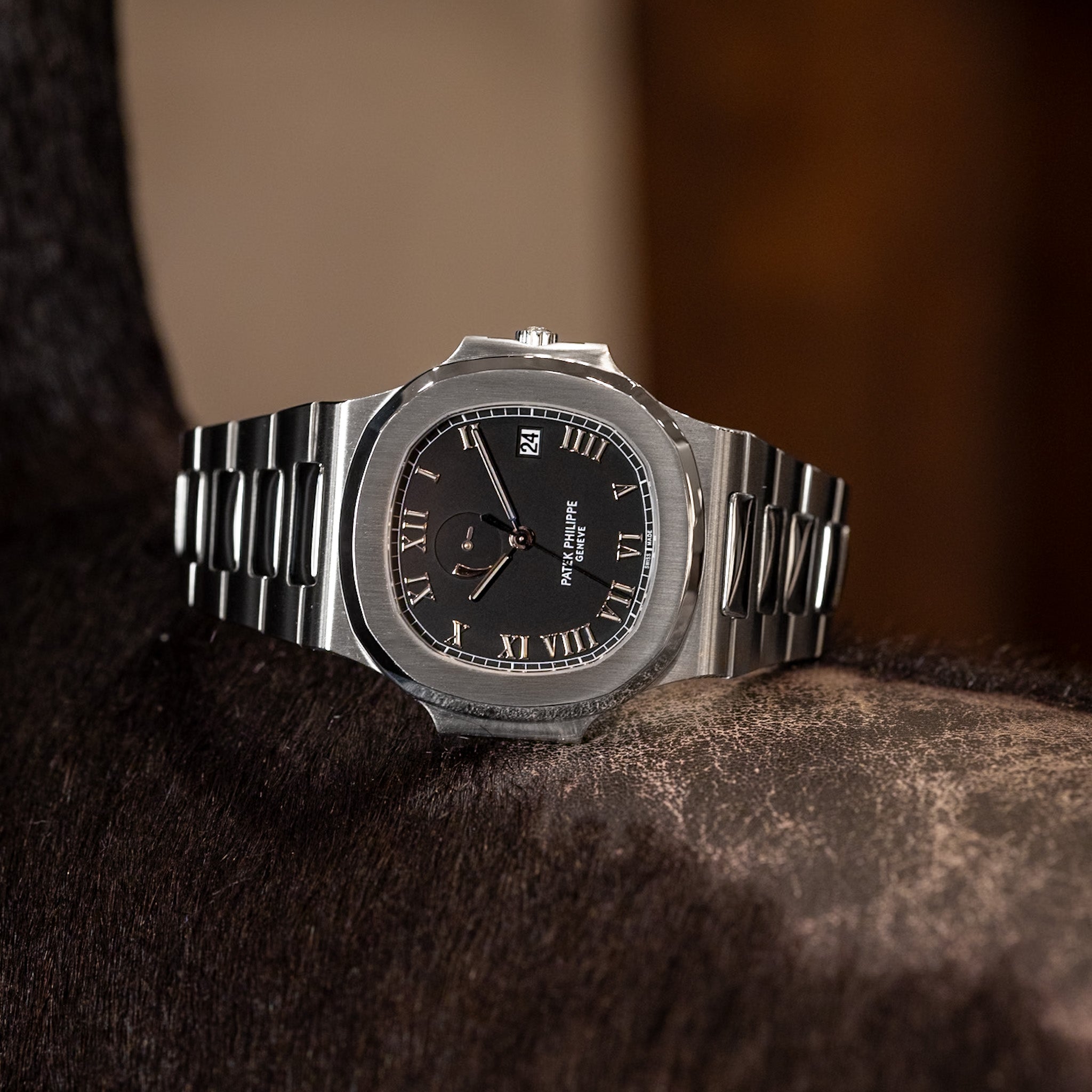 Silver watch with black face on a textured surface