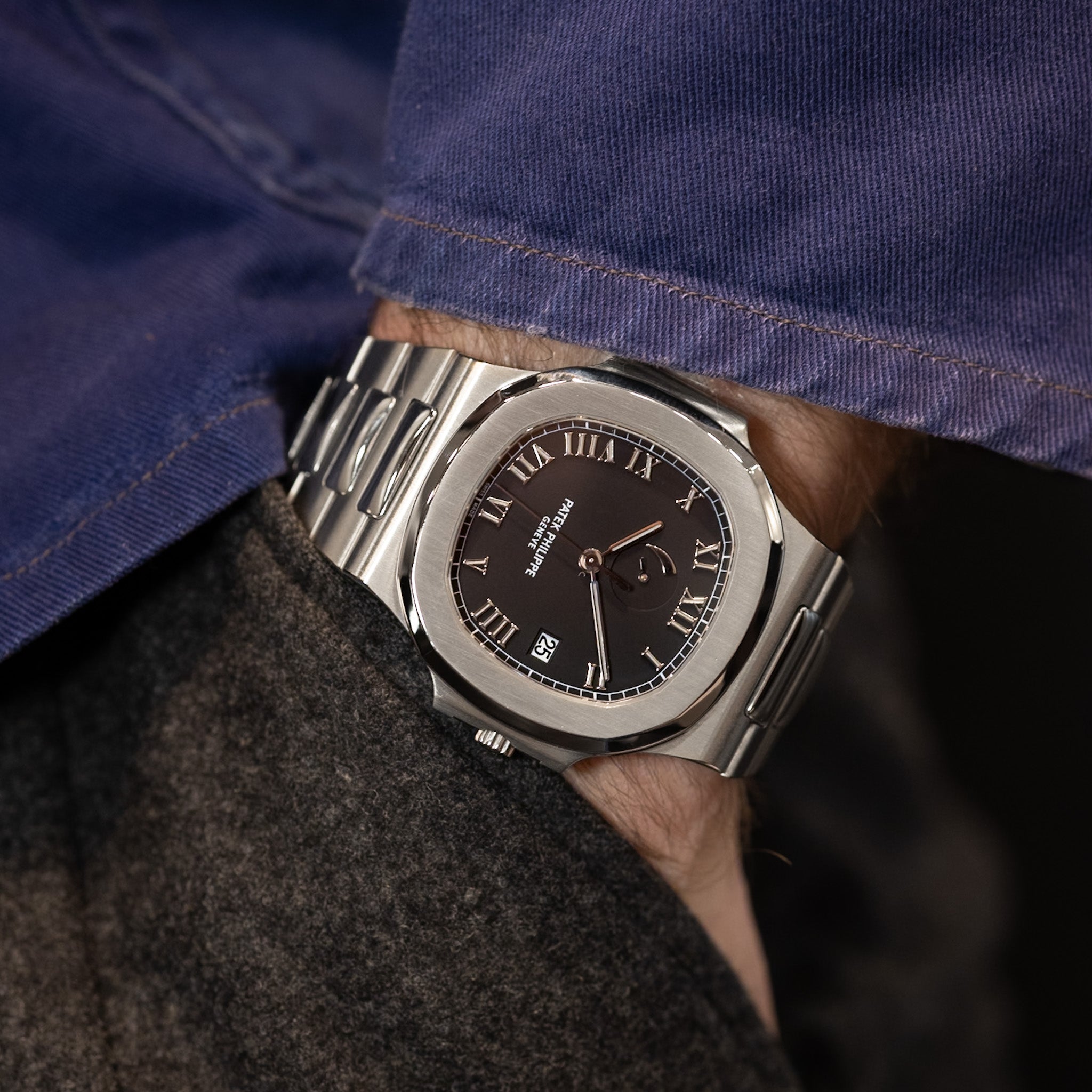 Close-up of a person wearing a silver wristwatch with a dark face.