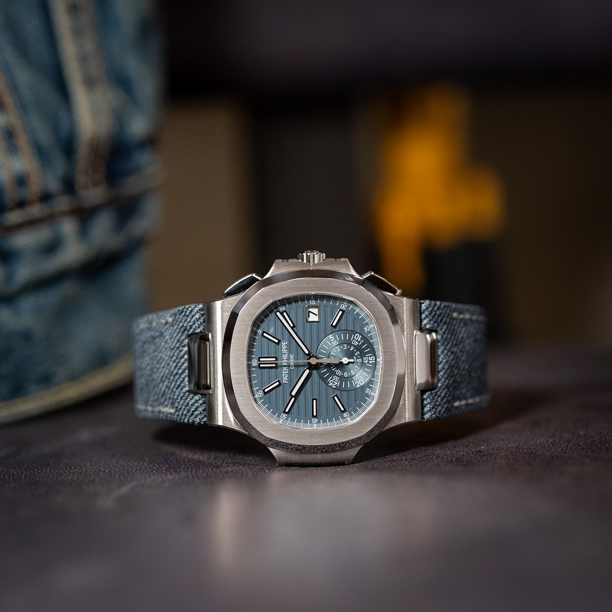 Watch with blue face and strap on a dark surface, blurred background