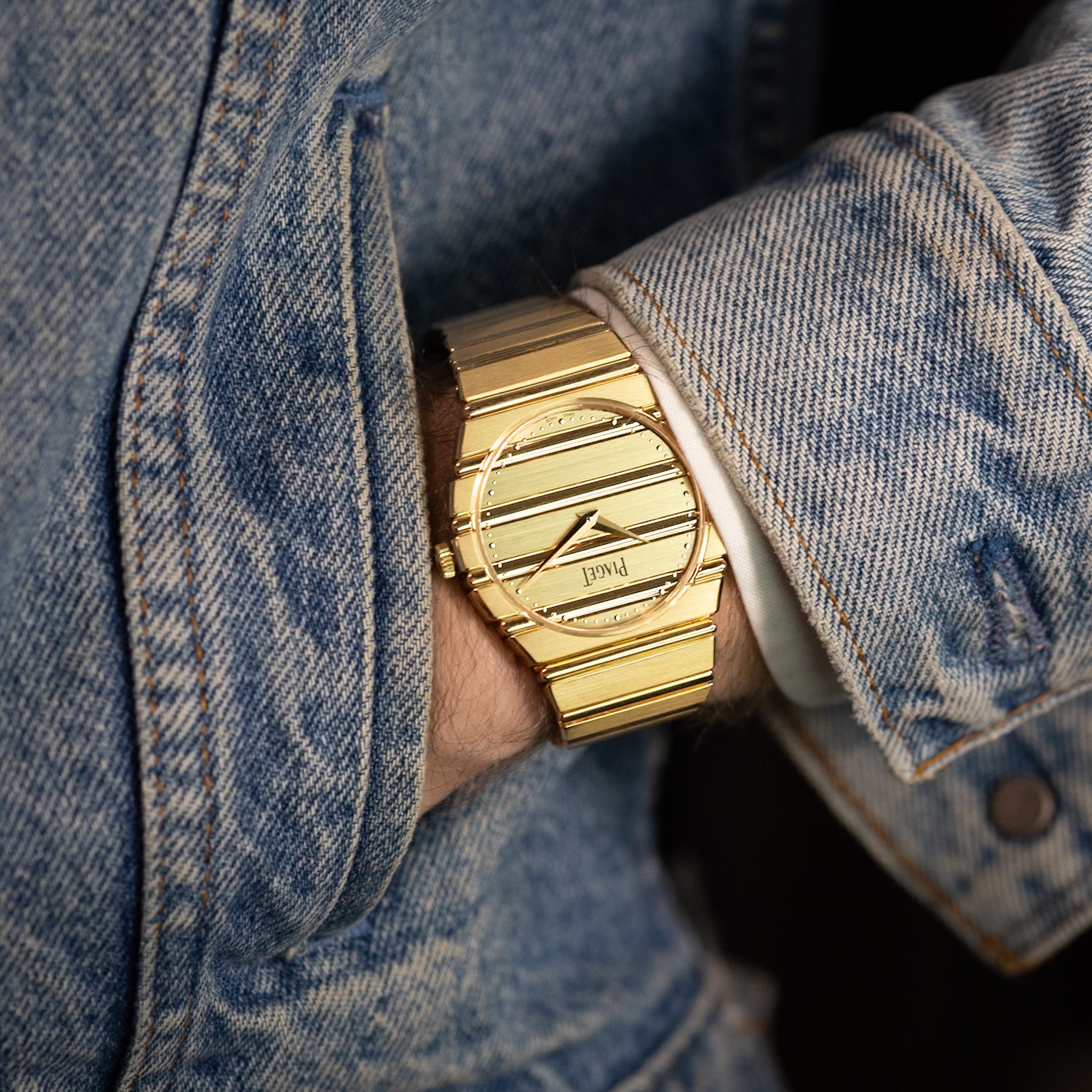 Gold watch on a wrist with a denim jacket
