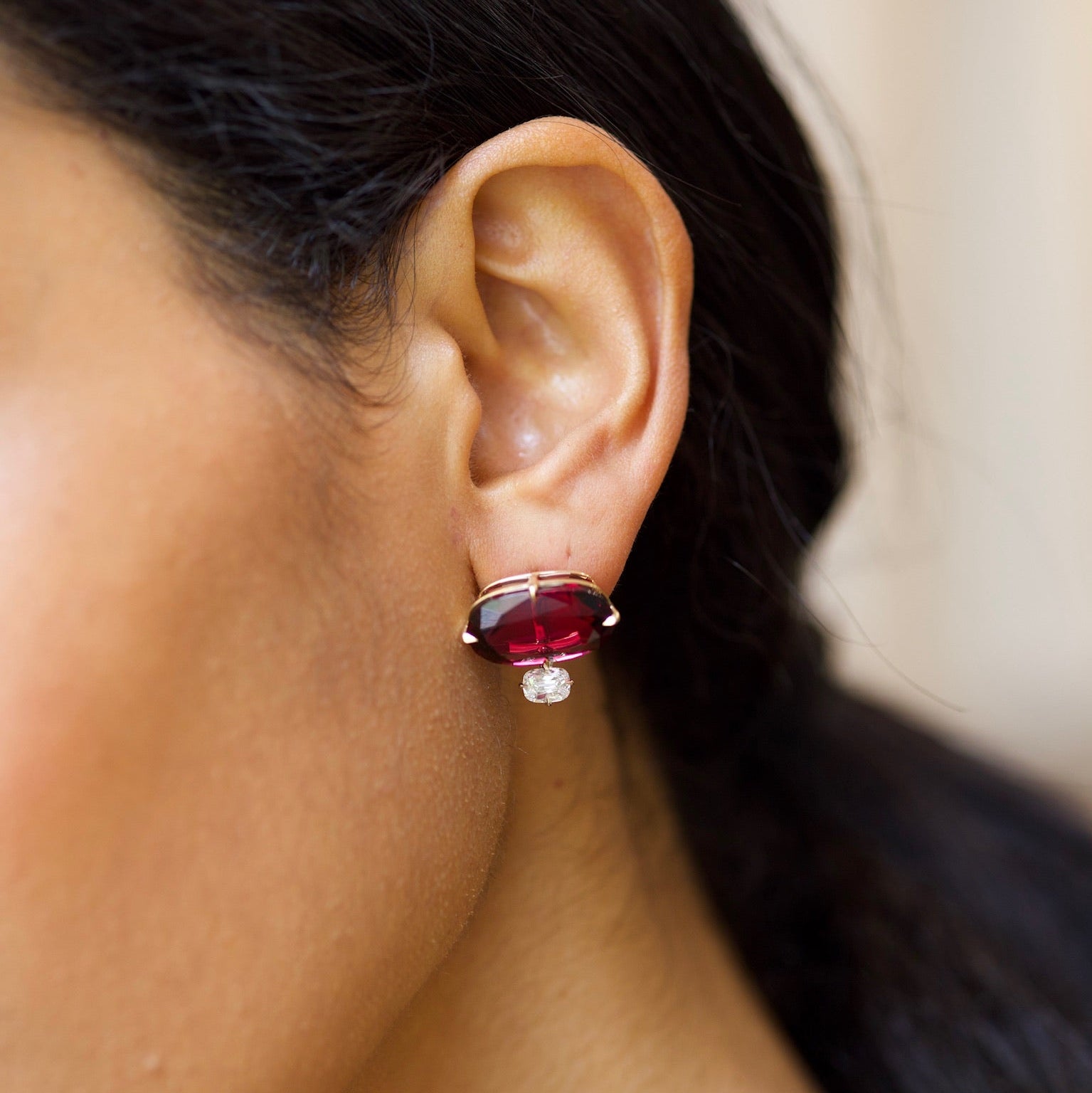 Close-up of a person wearing a red gemstone earring with a blurred background