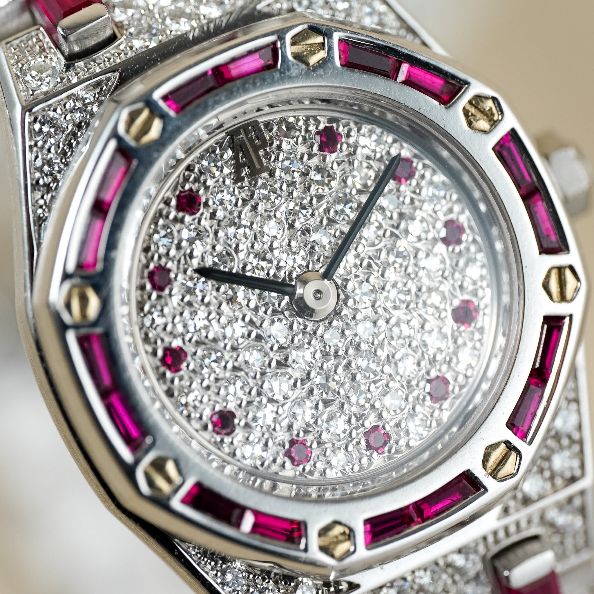 Luxury watch with diamond and ruby accents on a light background