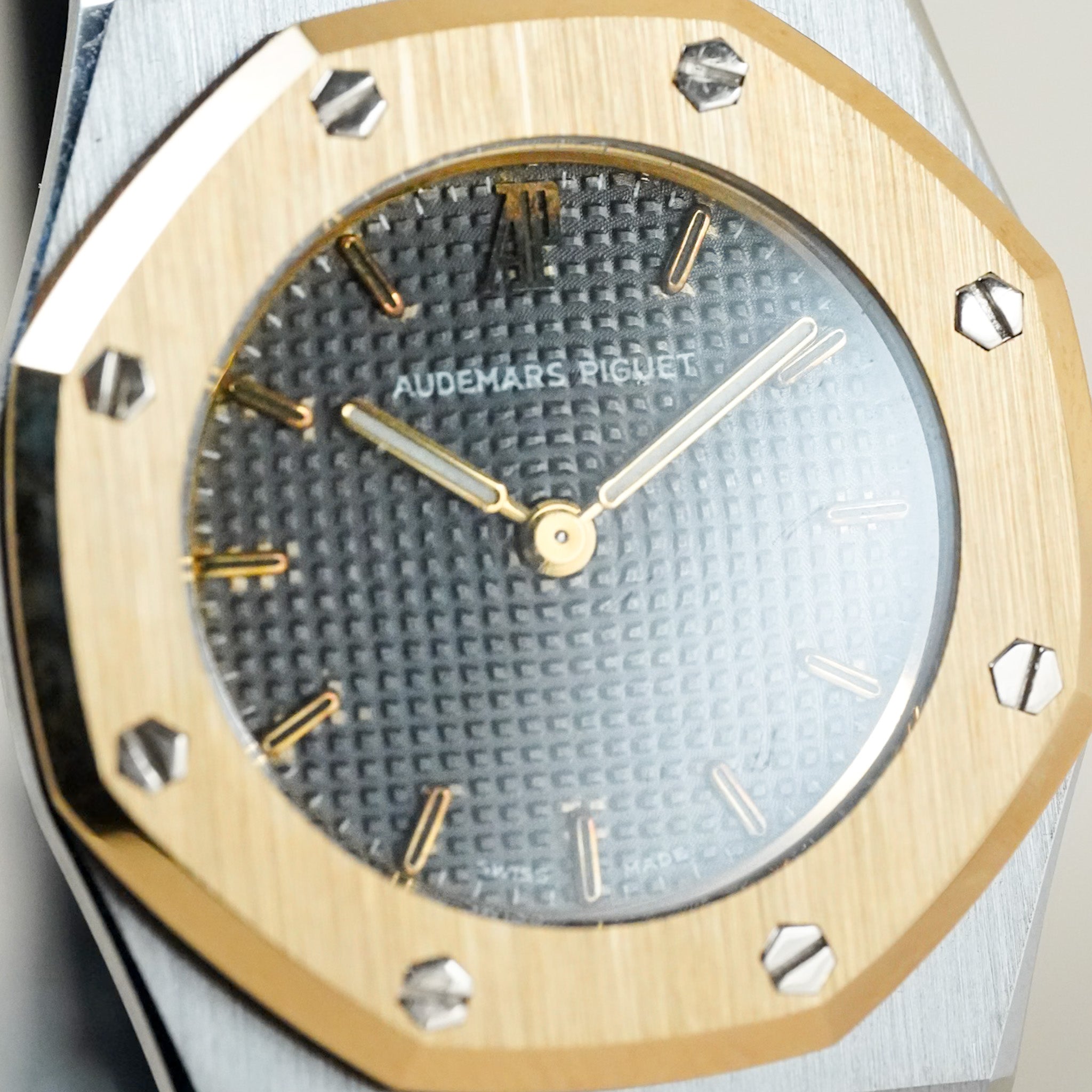 An Audemars Piguet Royal oak with a grey dial and a stainless steel & yellow gold case and bracelet, shot on a neutral cream background