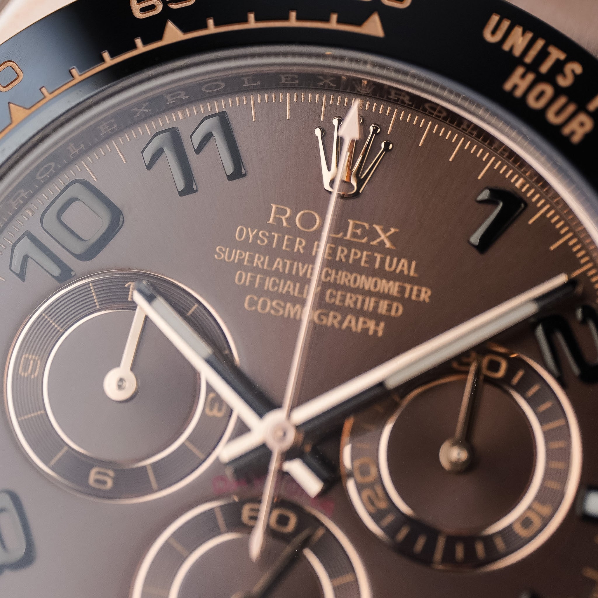 Closeup of a rose gold Rolex Daytona with a chocolate brown dial, rose gold accents, and a black ceramic bezel. 