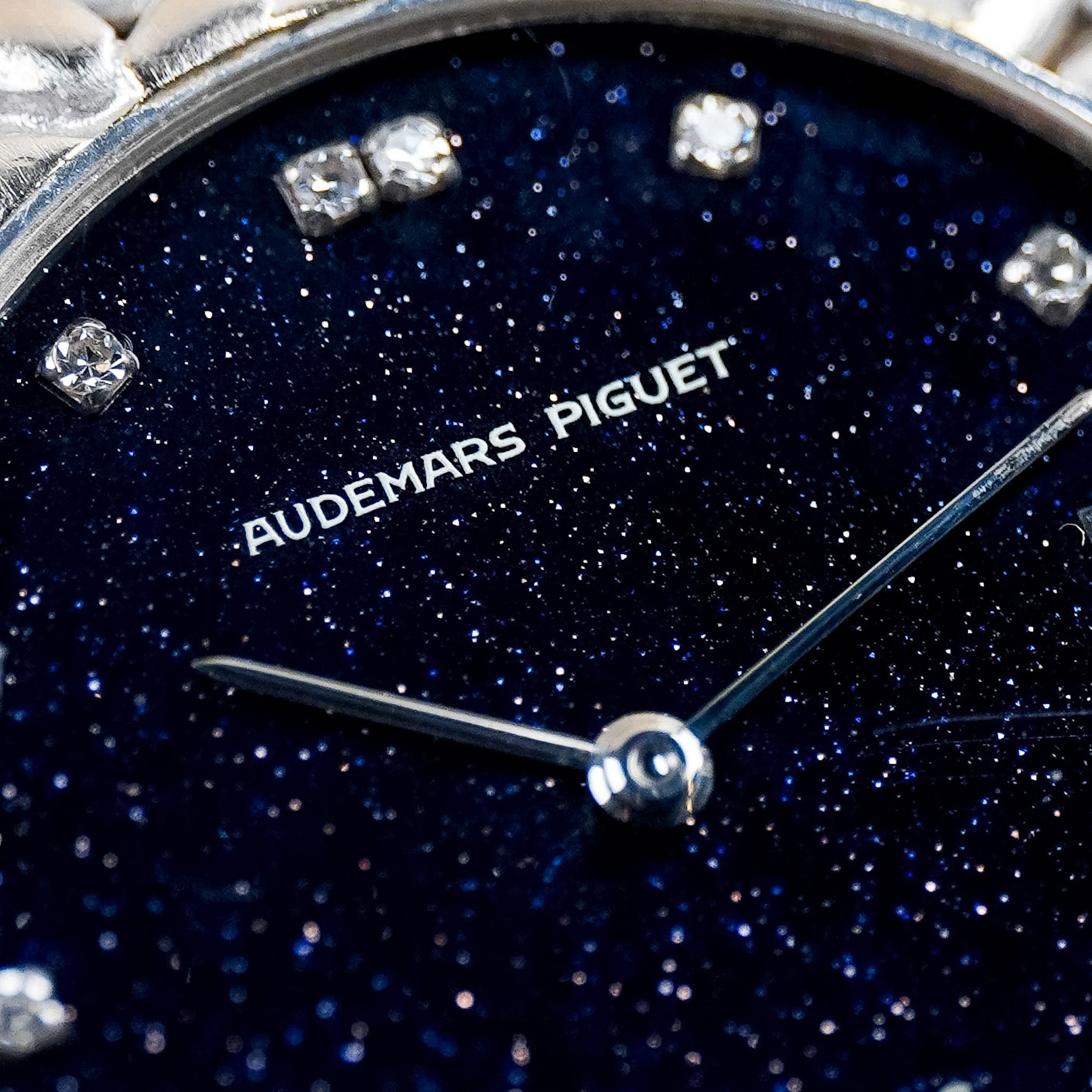 Closeup of an Audemars Piguet watch dial. The dial is made of a sparkly blue Aventurine with diamond hour markers, white gold hands, and AUDEMARS PIGUET printed on the dial