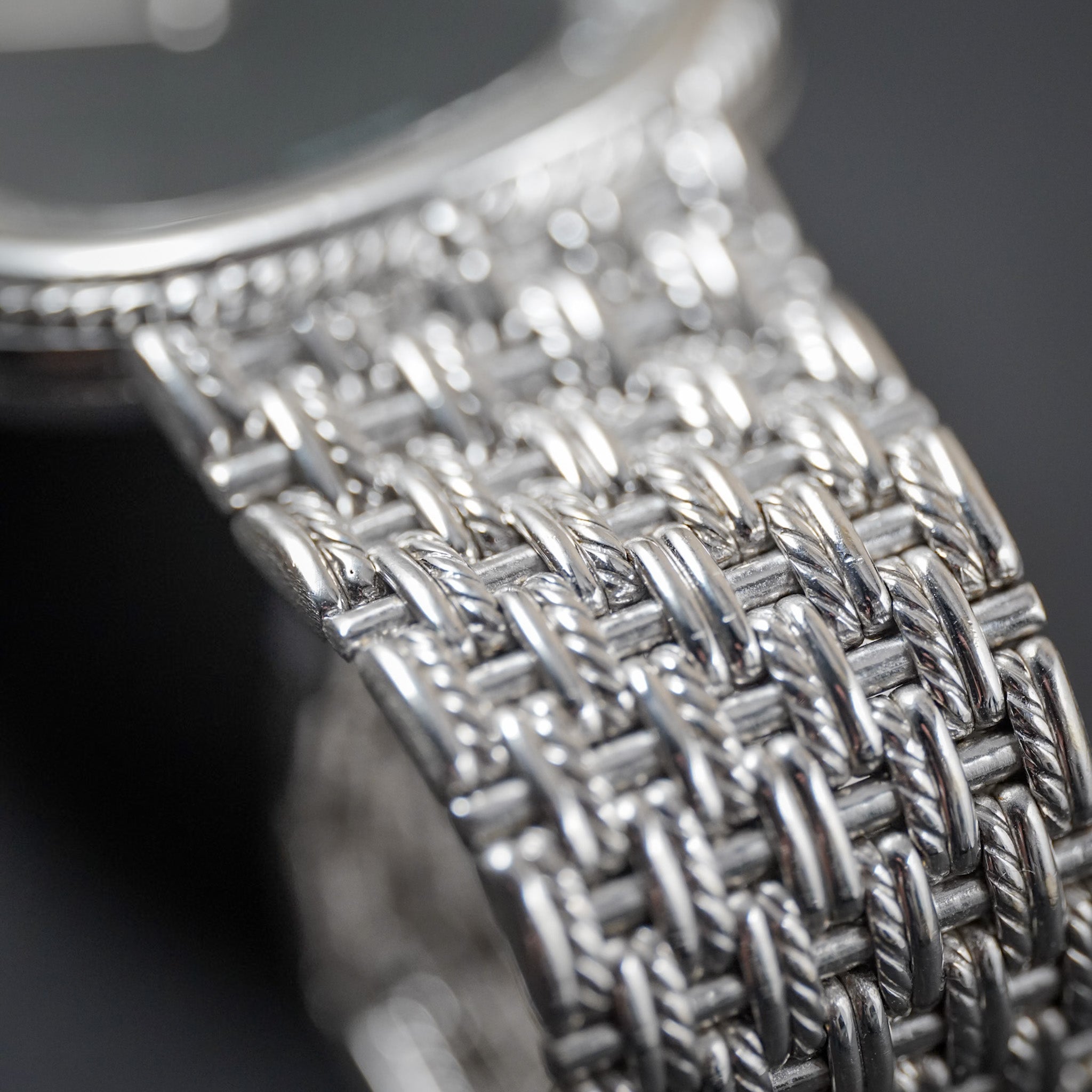 Close-up of a richly-textured, woven white gold watch bracelet