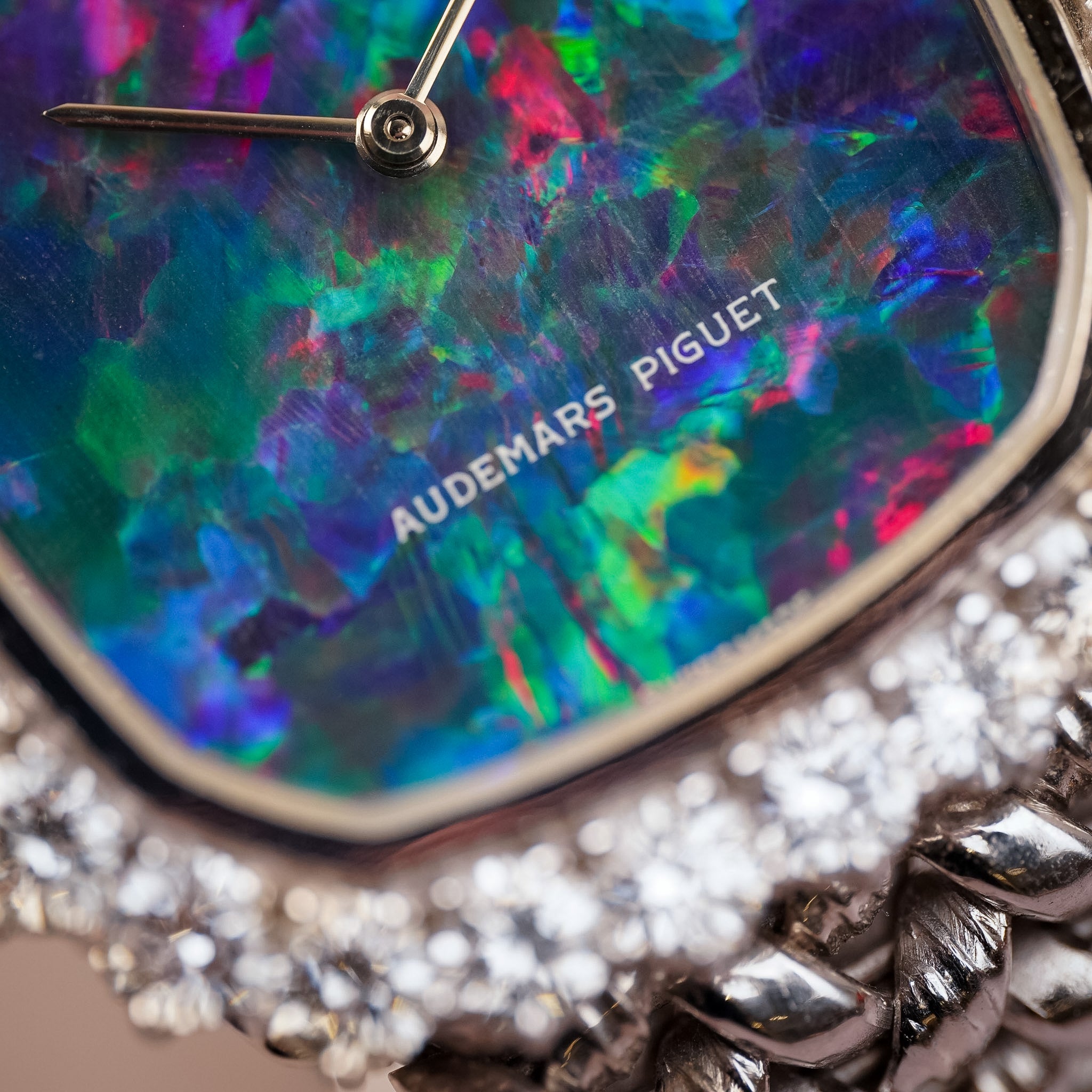 Close-up of an Audemars Piguet watch featuring a vibrant, multicolored iridescent opal dial and a silver-toned pavé diamond bracelet.