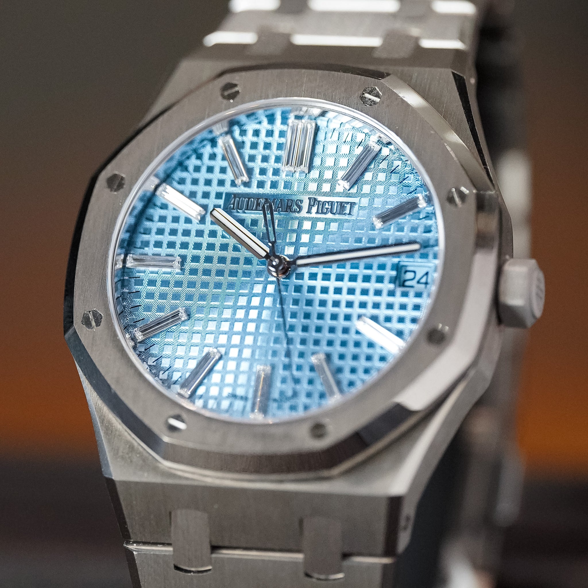 White gold watch with baguette diamond hour markers and an ice blue dial with a blurry background