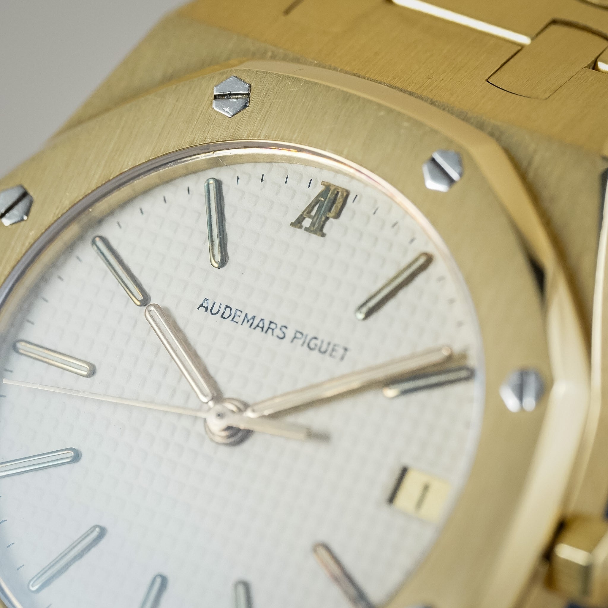 Close-up of an Audemars Piguet watch with a gold octagonal bezel, white dial, and matching gold bracelet.