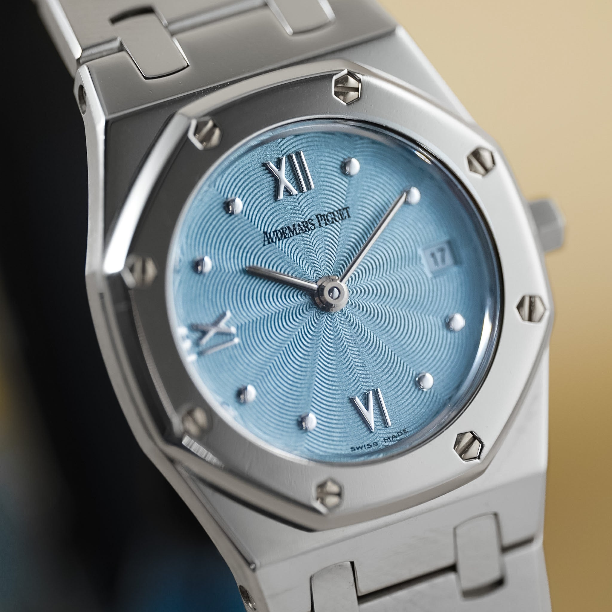 A close-up shot of an Audemars Piguet Royal Oak watch featuring a light blue sunburst dial, silver-tone case, and matching stainless steel bracelet.