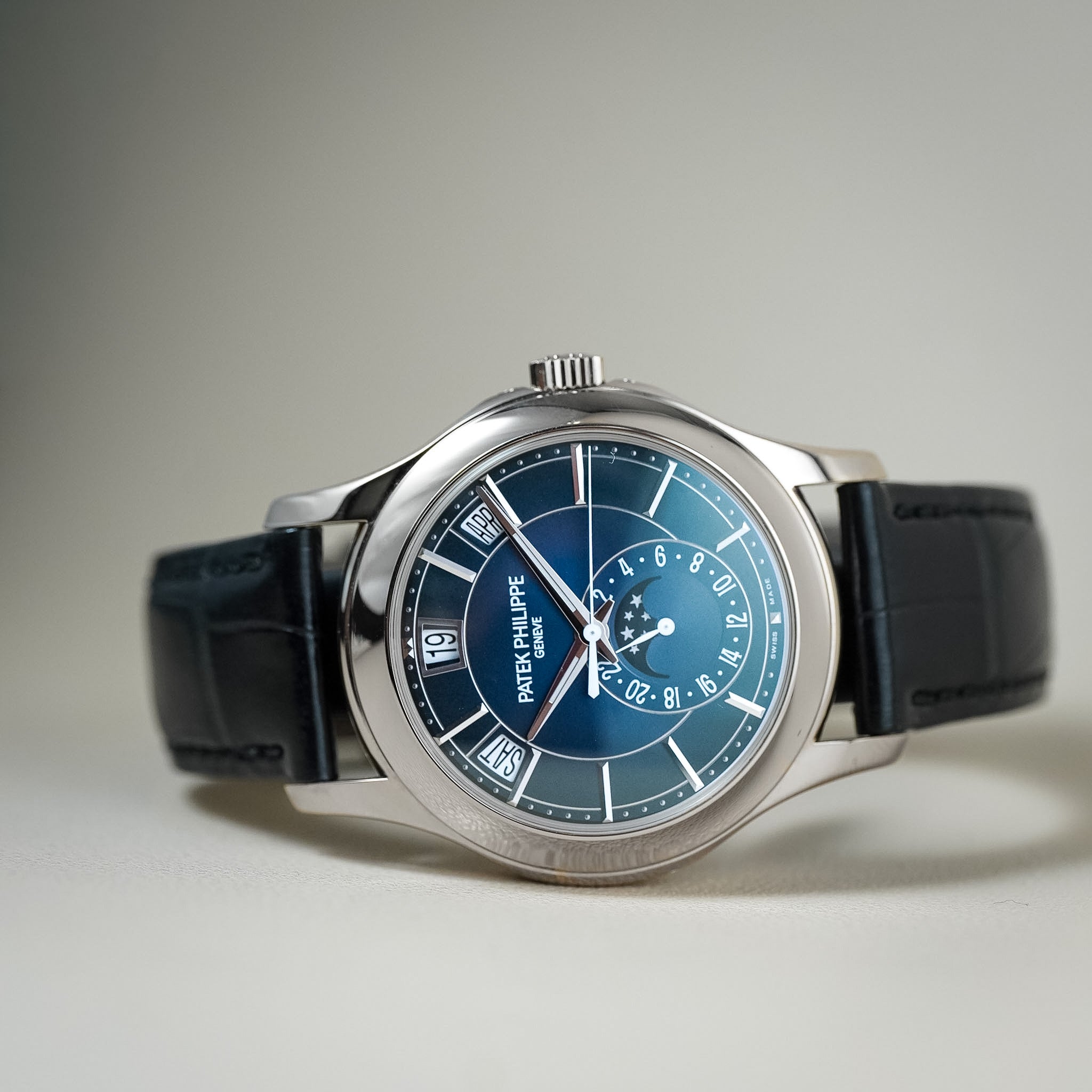 Luxury platinum watch with a blue dial laying on its side