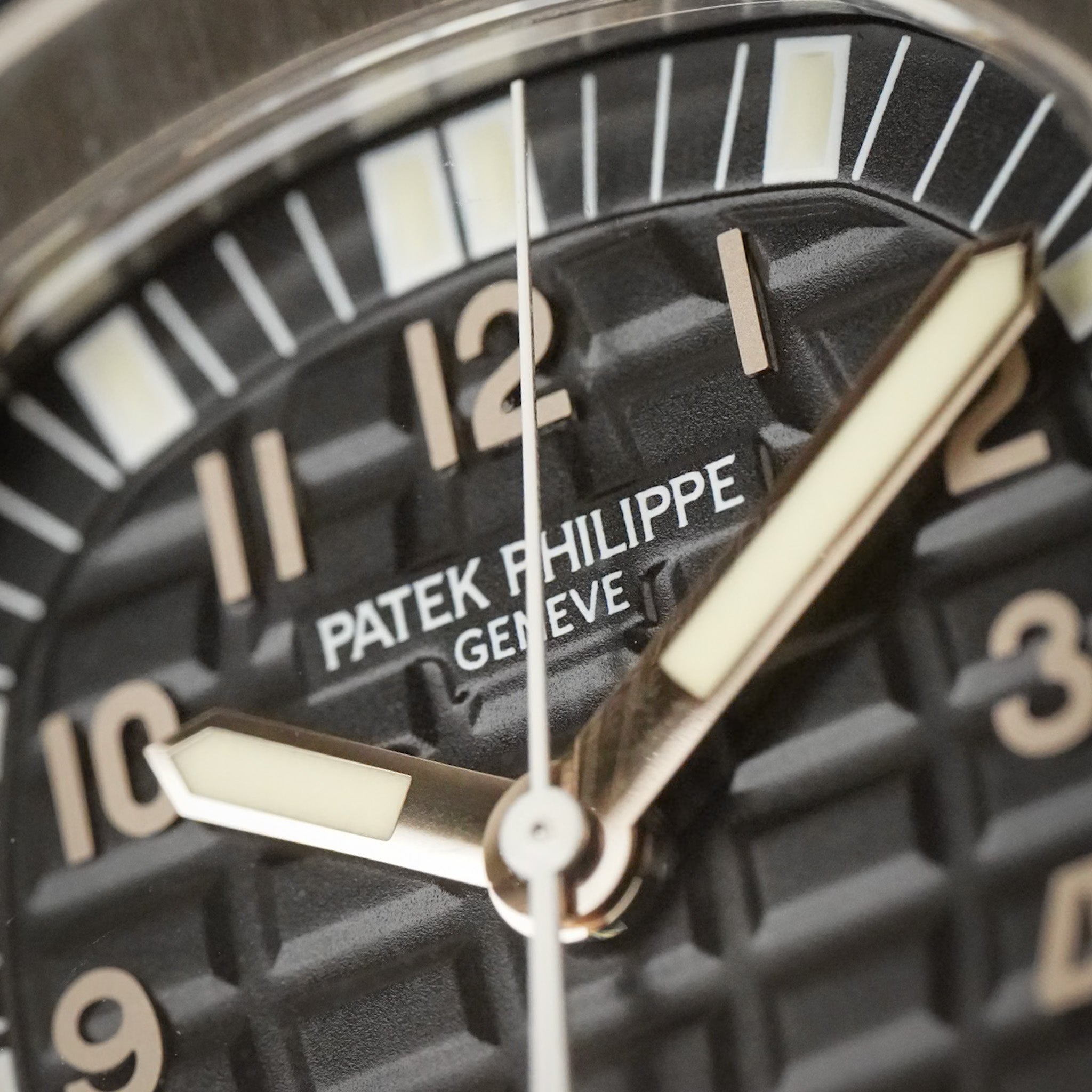 Closeup of a stainless steel Patek Philippe Aquanaut sport watch with a textured black dial, and white hands and hour markers