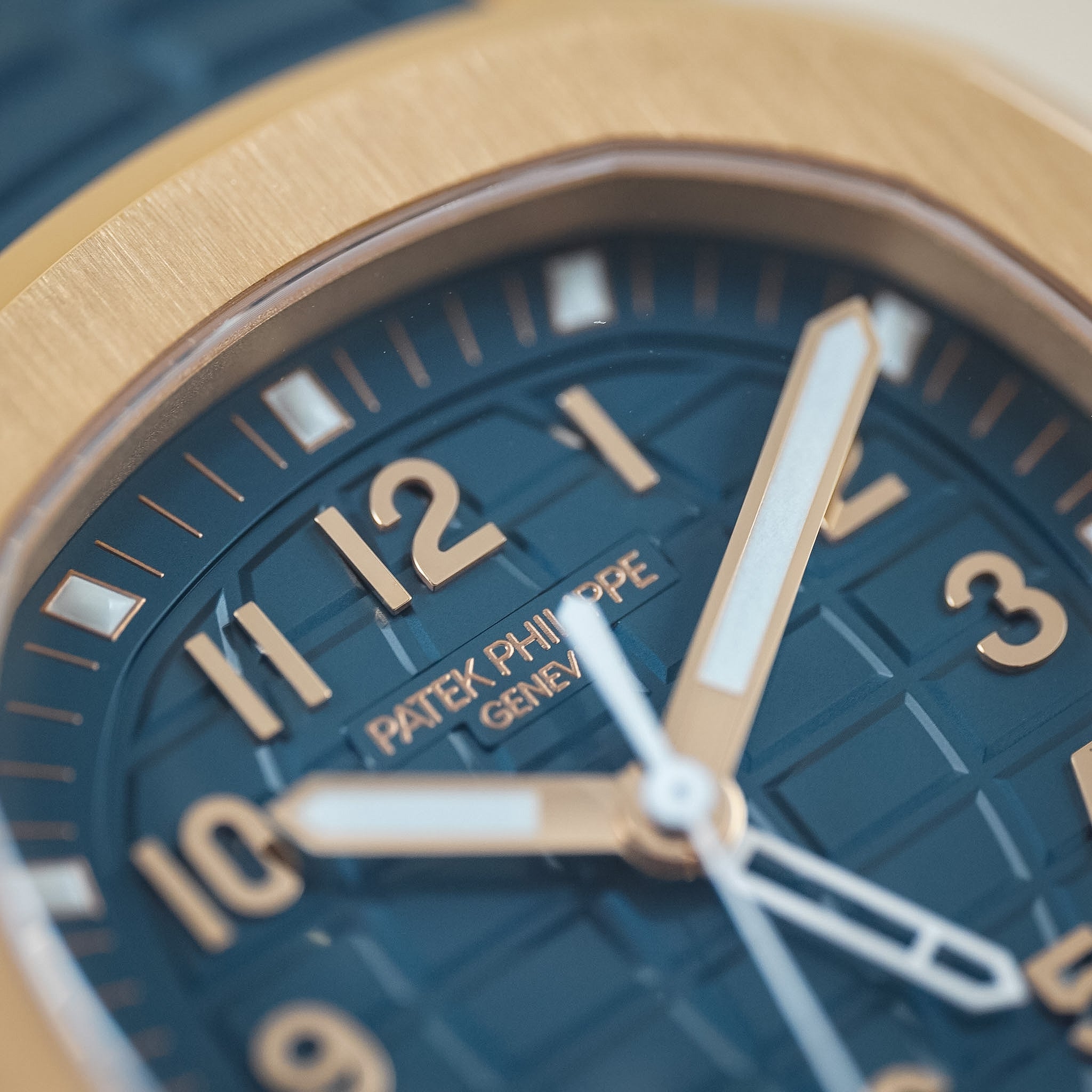 Close-up of a Patek Philippe wristwatch with a dark blue textured dial, gold-tone bezel and hour markers, and silver-tone hands.