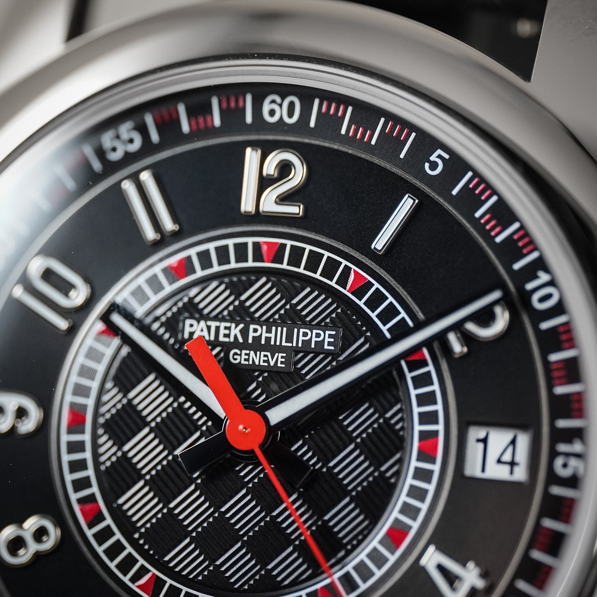 Close up of a Patek Philippe white gold watch featuring a black textured dial, red seconds hand, and white hour numerals.