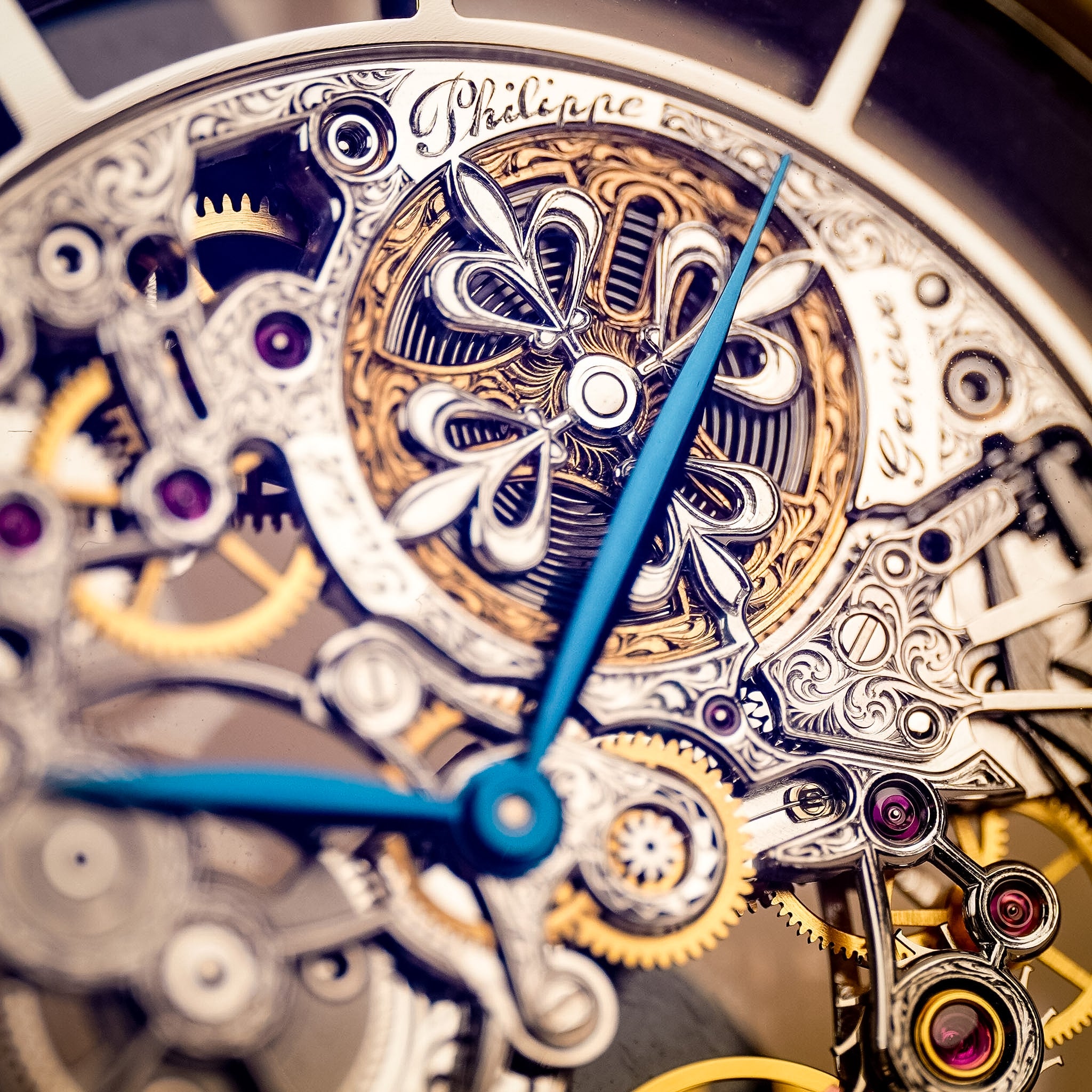 Closeup of a A white gold Patek Philippe watch with an intricately decorated skeletonized movement and blue hands