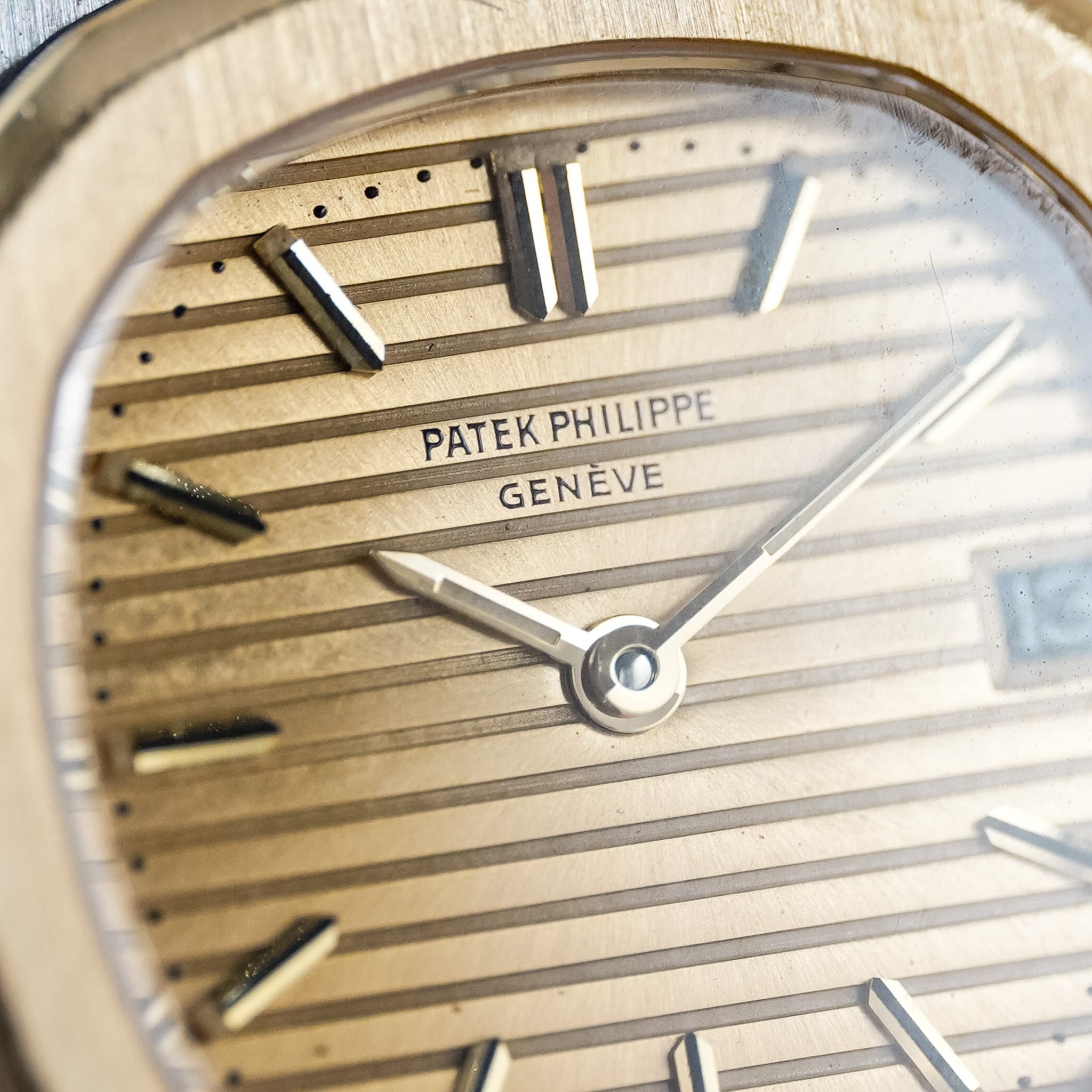 Close-up shot of a Patek Philippe Nautilus 4700 with a textured, gold dial with gold hands and hour markers