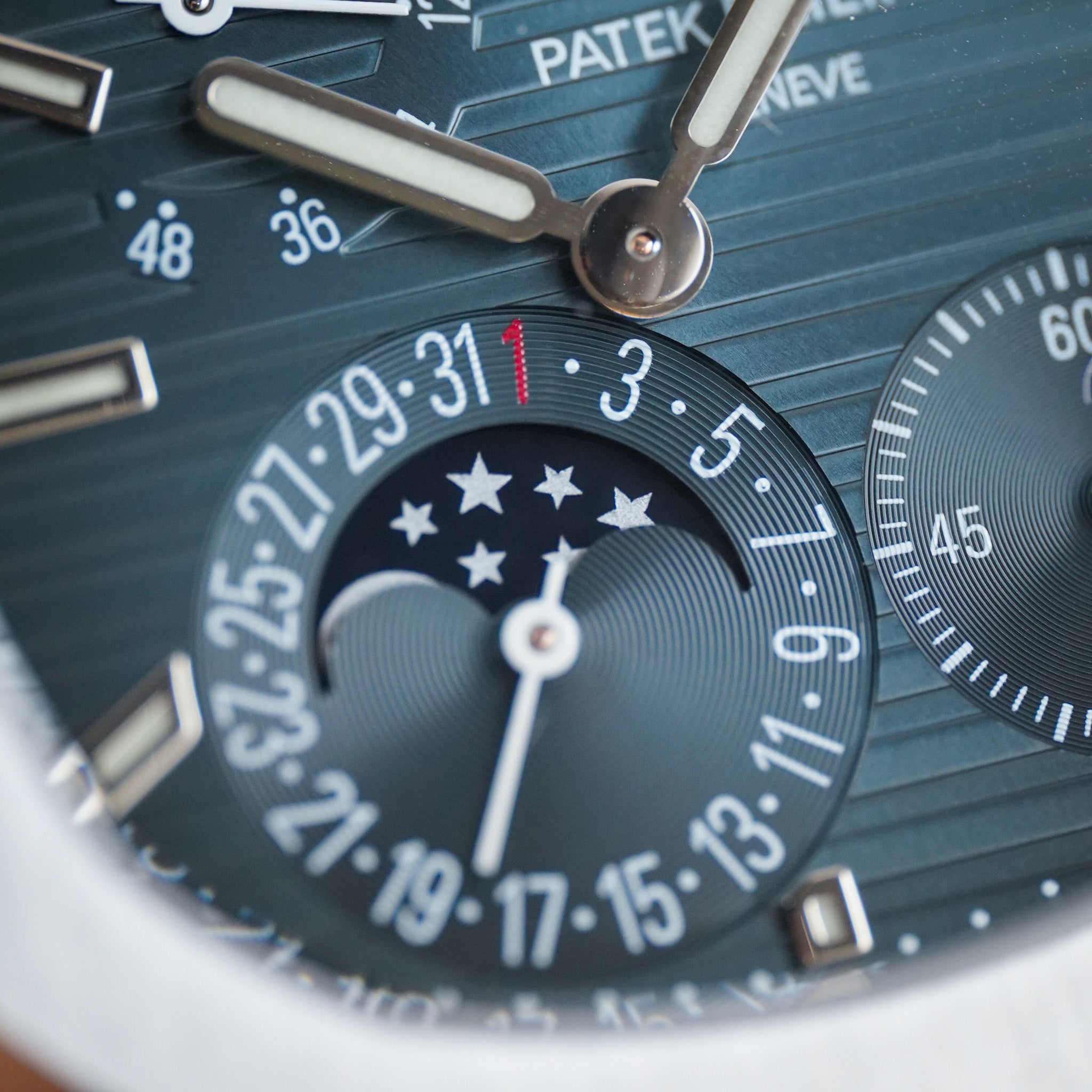 Close-up of a Patek Philippe wristwatch dial with a dark blue textured dial, silver-tone hands, and a moonphase subdial.