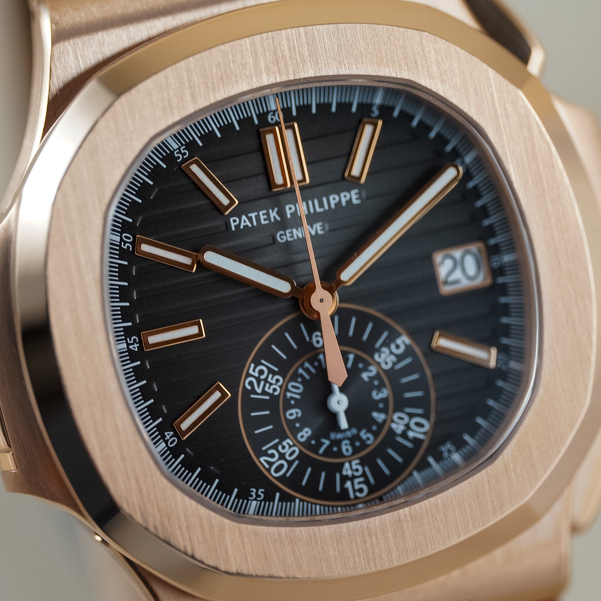 Close-up of a Patek Philippe wristwatch with a brushed rose gold-toned case and a dark charcoal gray sunburst dial, featuring rose gold hour markers and hands.