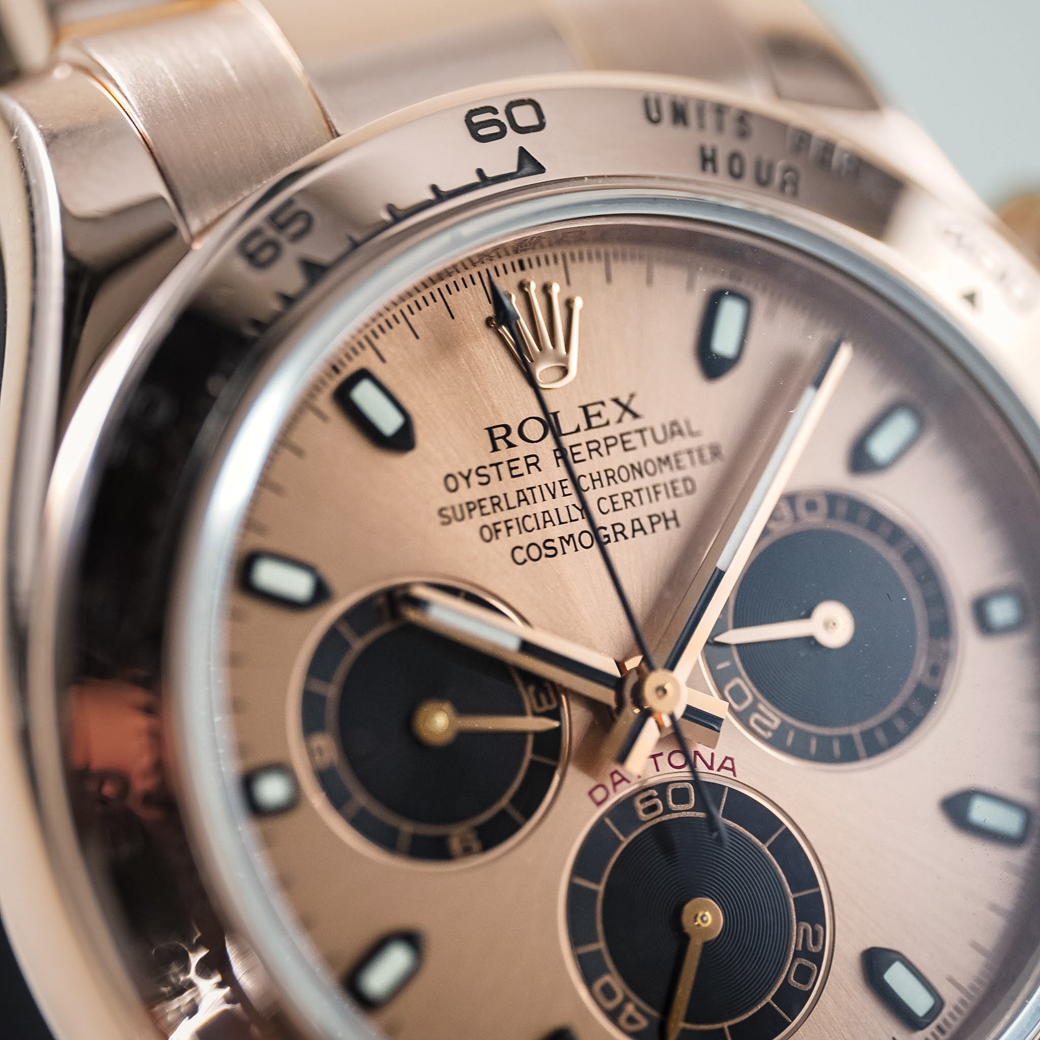 Close-up of a Rolex Daytona watch with a champagne dial, dark blue subdials, and a stainless steel bezel.