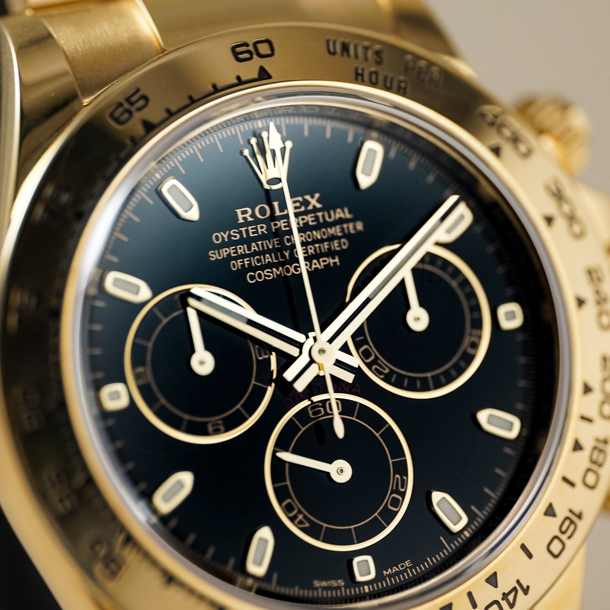Close-up of a Rolex Oyster Perpetual Cosmograph Daytona watch with a gold-tone case, black dial, and gold-tone bezel markings.