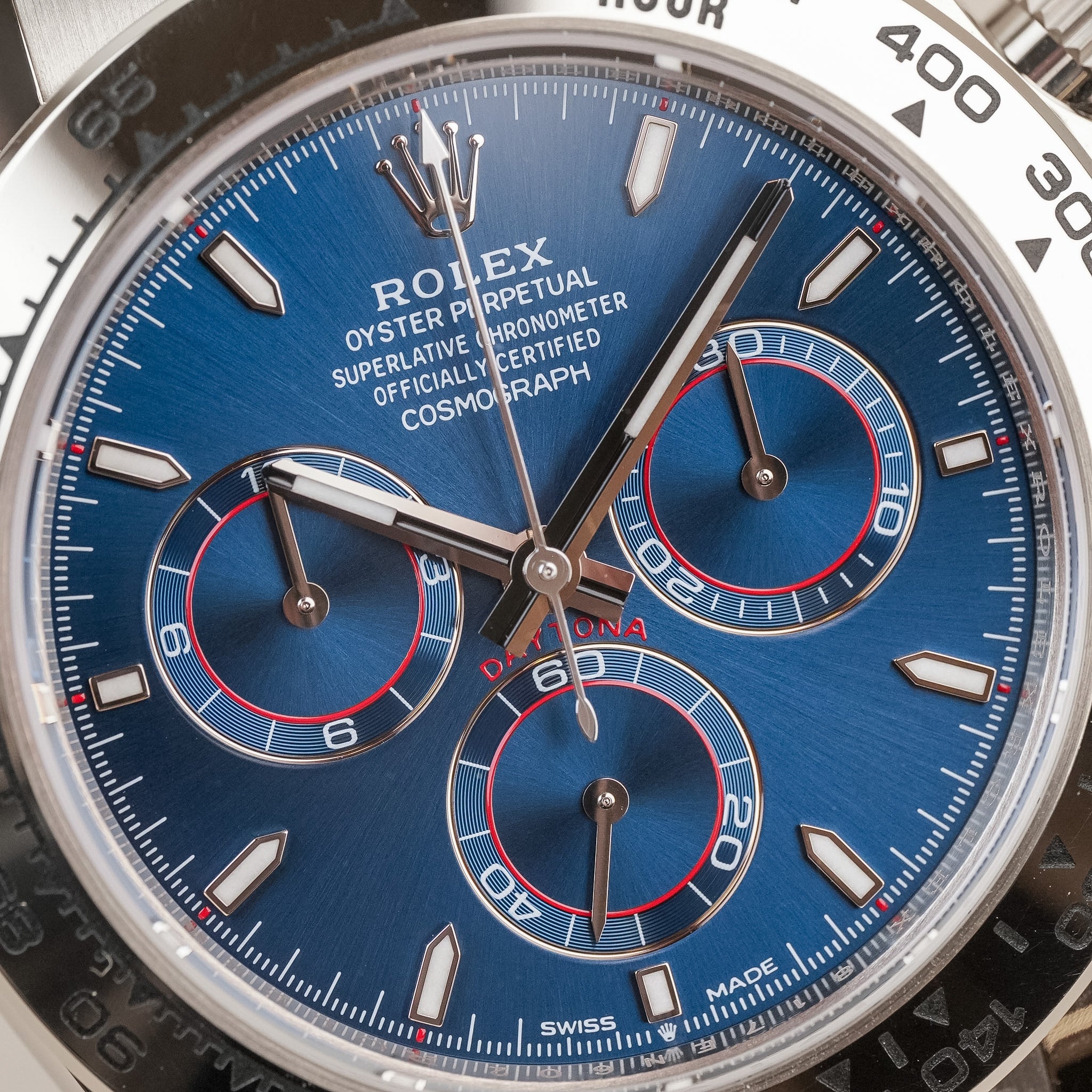 Closeup of a A white gold Rolex Daytona with a blue dial and red accents