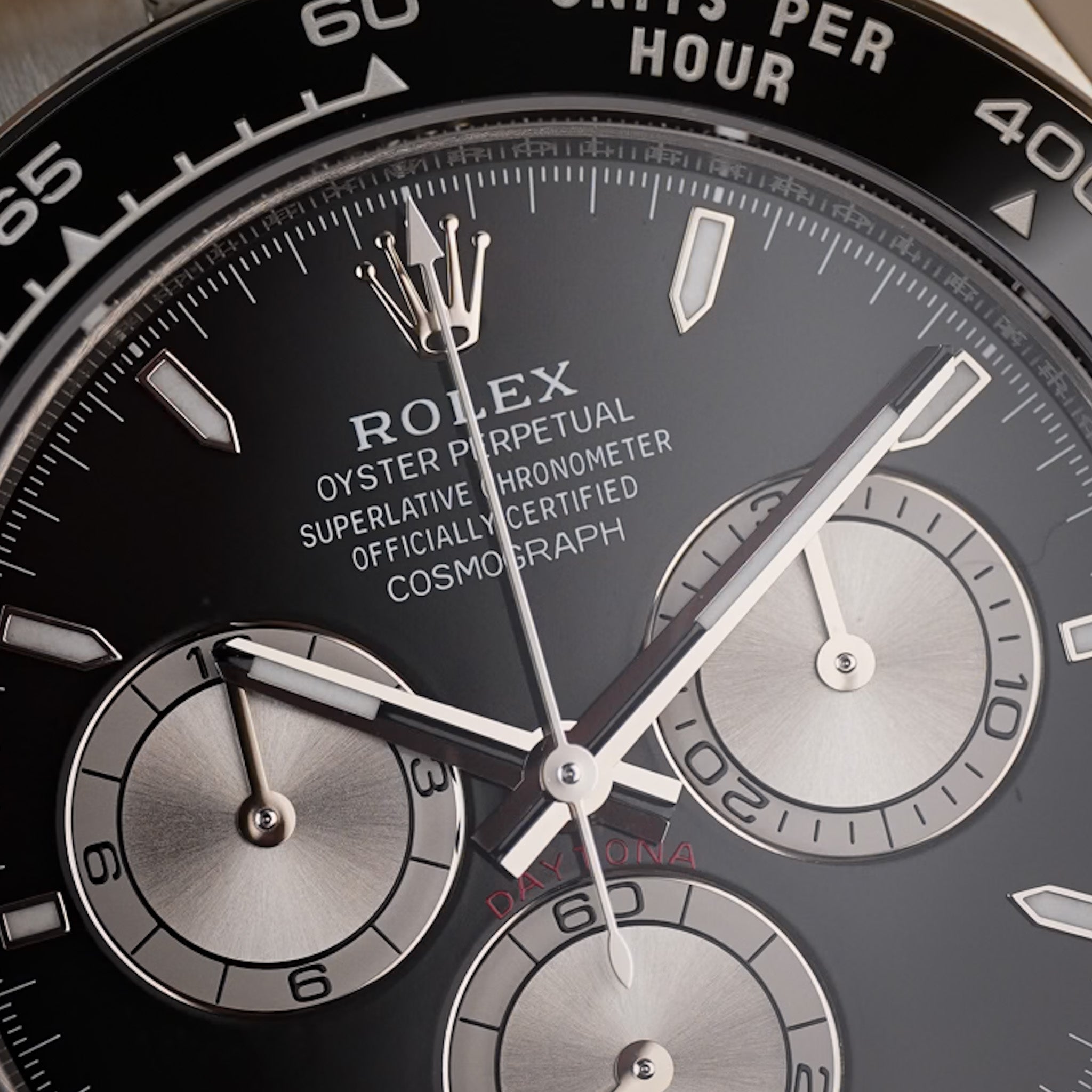 Close-up of a Rolex Oyster Perpetual Superlative Chronometer Cosmograph watch dial with a black bezel and silver-toned chronograph subdials.
