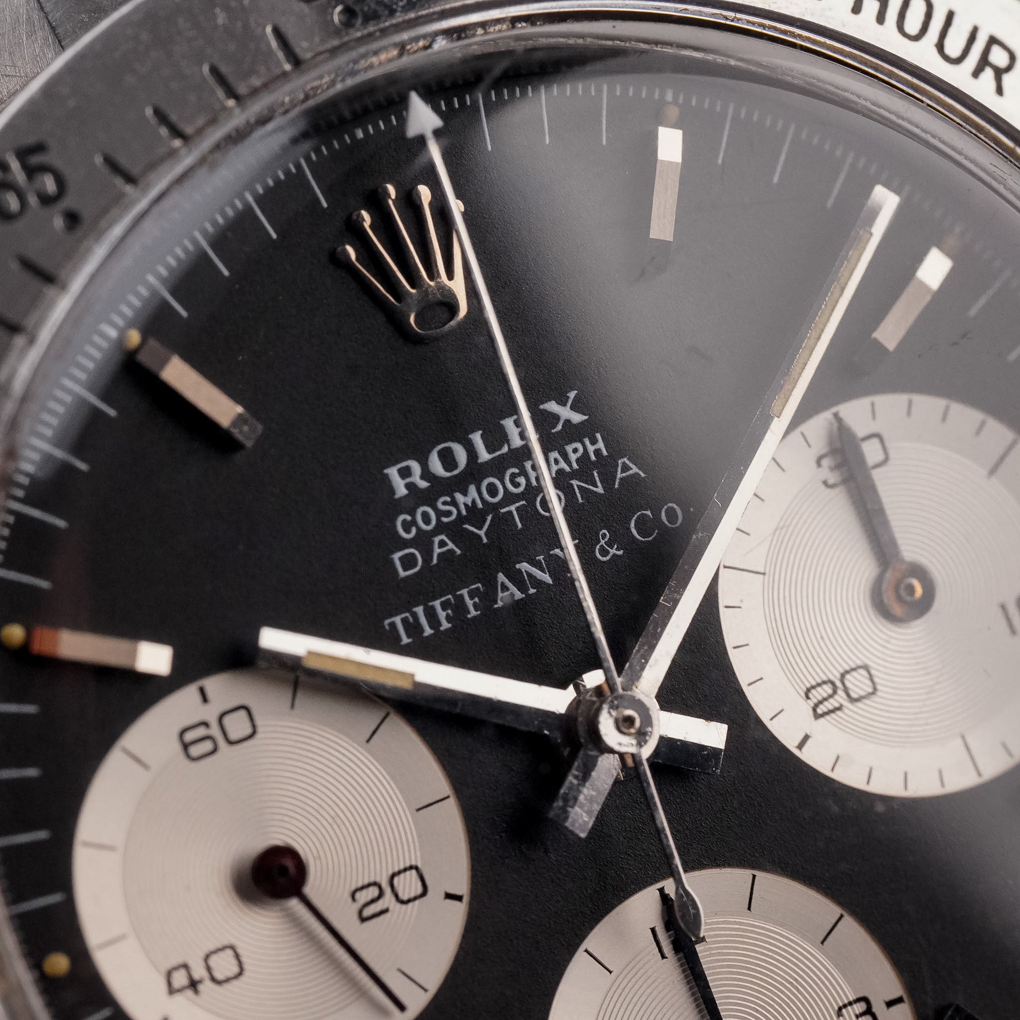 Closeup of a A steel vintage Rolex Daytona with a lack dial, white subdials, and steel bezel. One can read the text Rolex Cosmograph Daytona Tiffany & Co. on the dial.