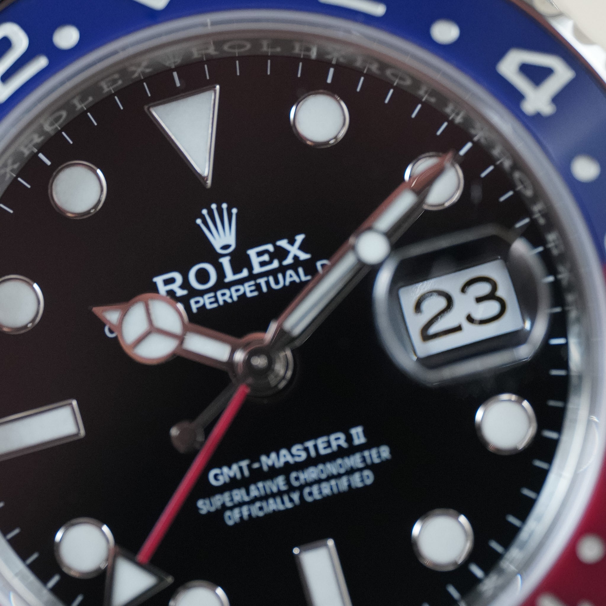 Closeup of a Rolex GMT-Master II watch with a blue and red bezel, black dial, and a date window showing 23. 
