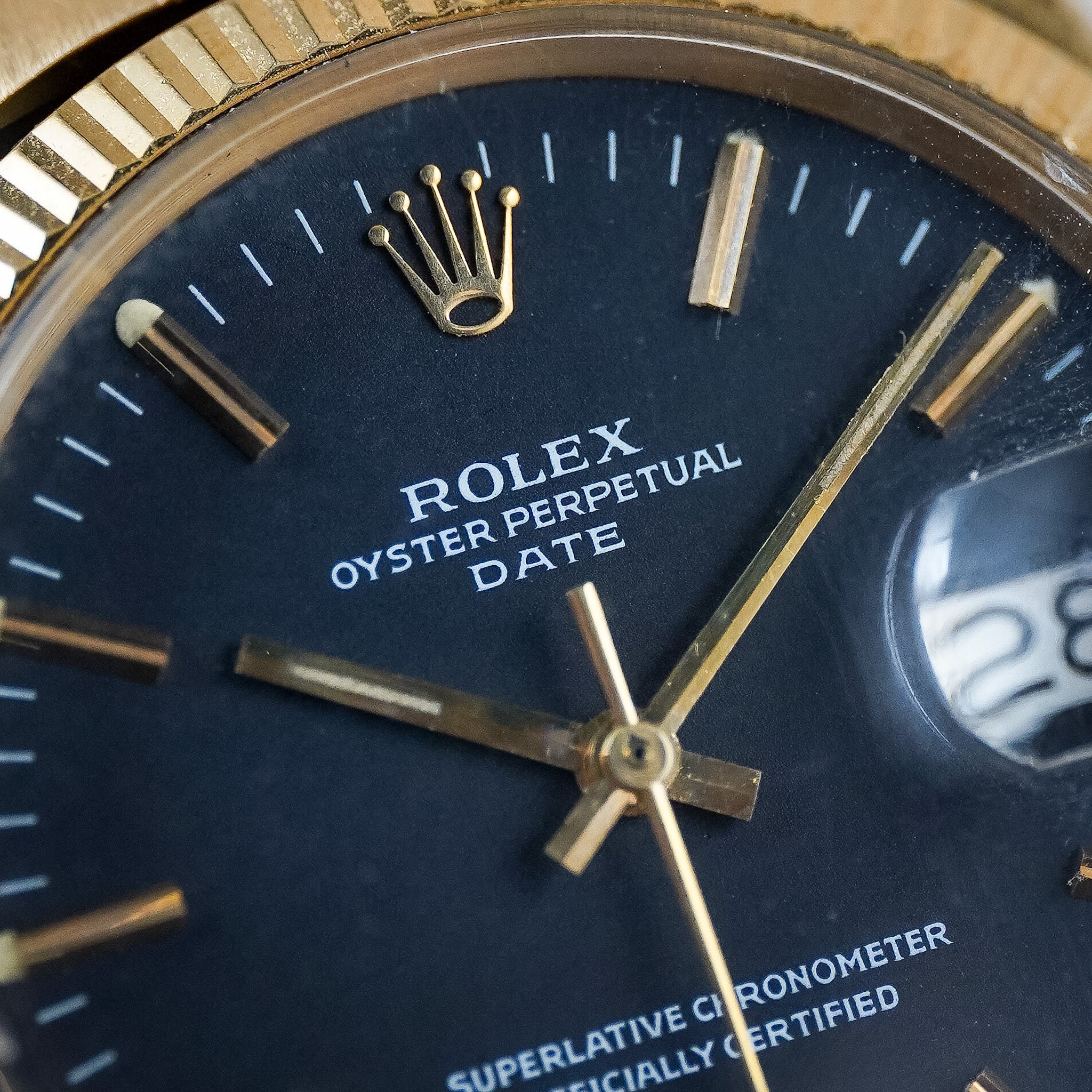 Close-up of a black dial Rolex watch with a yellow gold fluted bezel