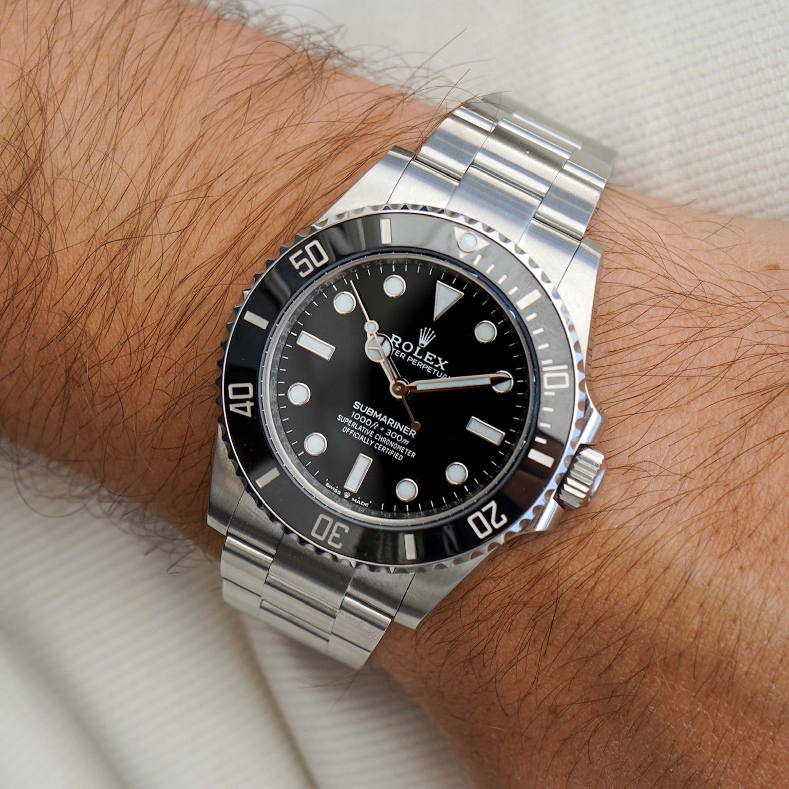 Silver watch with black dial on a wrist against a white background