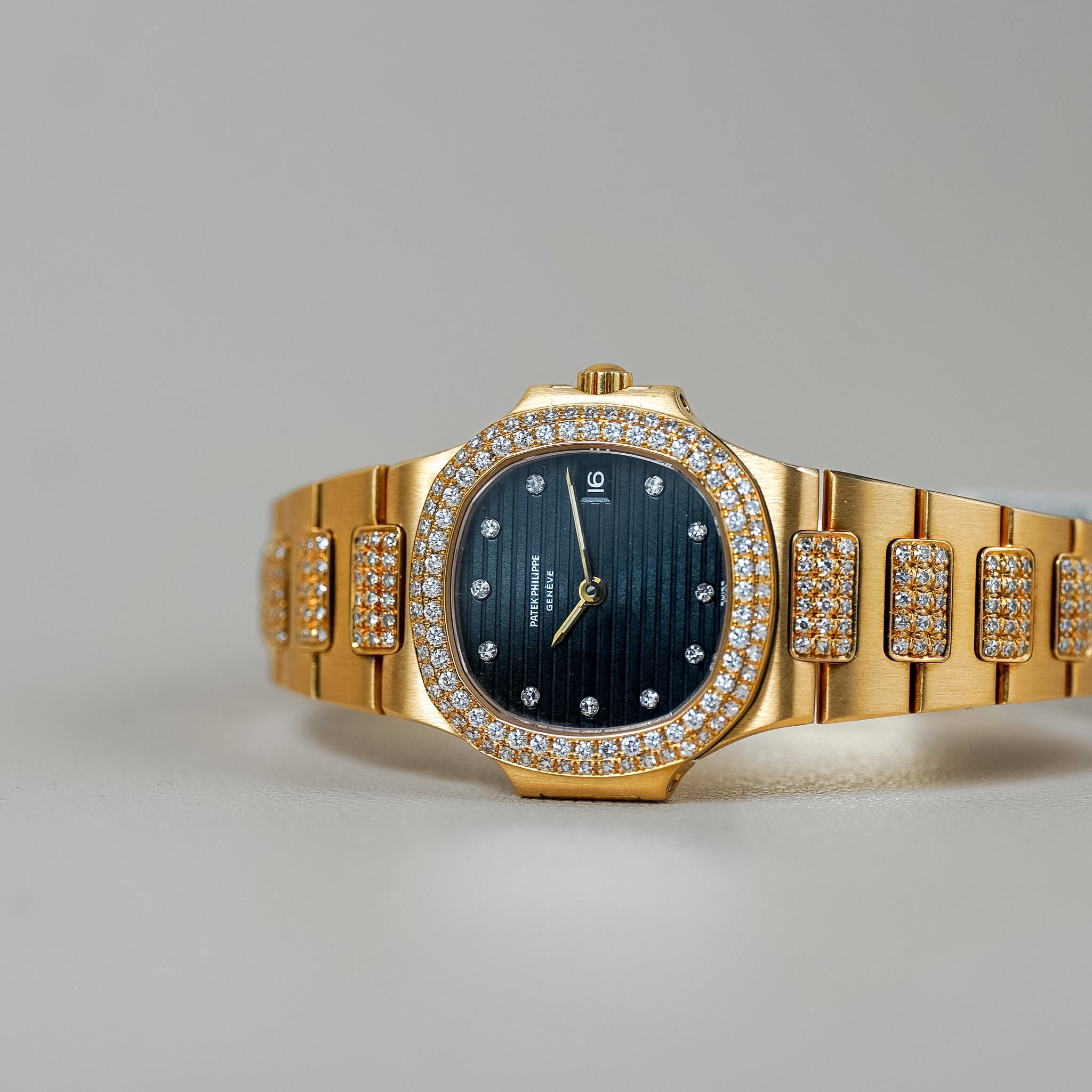 Gold wristwatch with diamond accents on a gray background