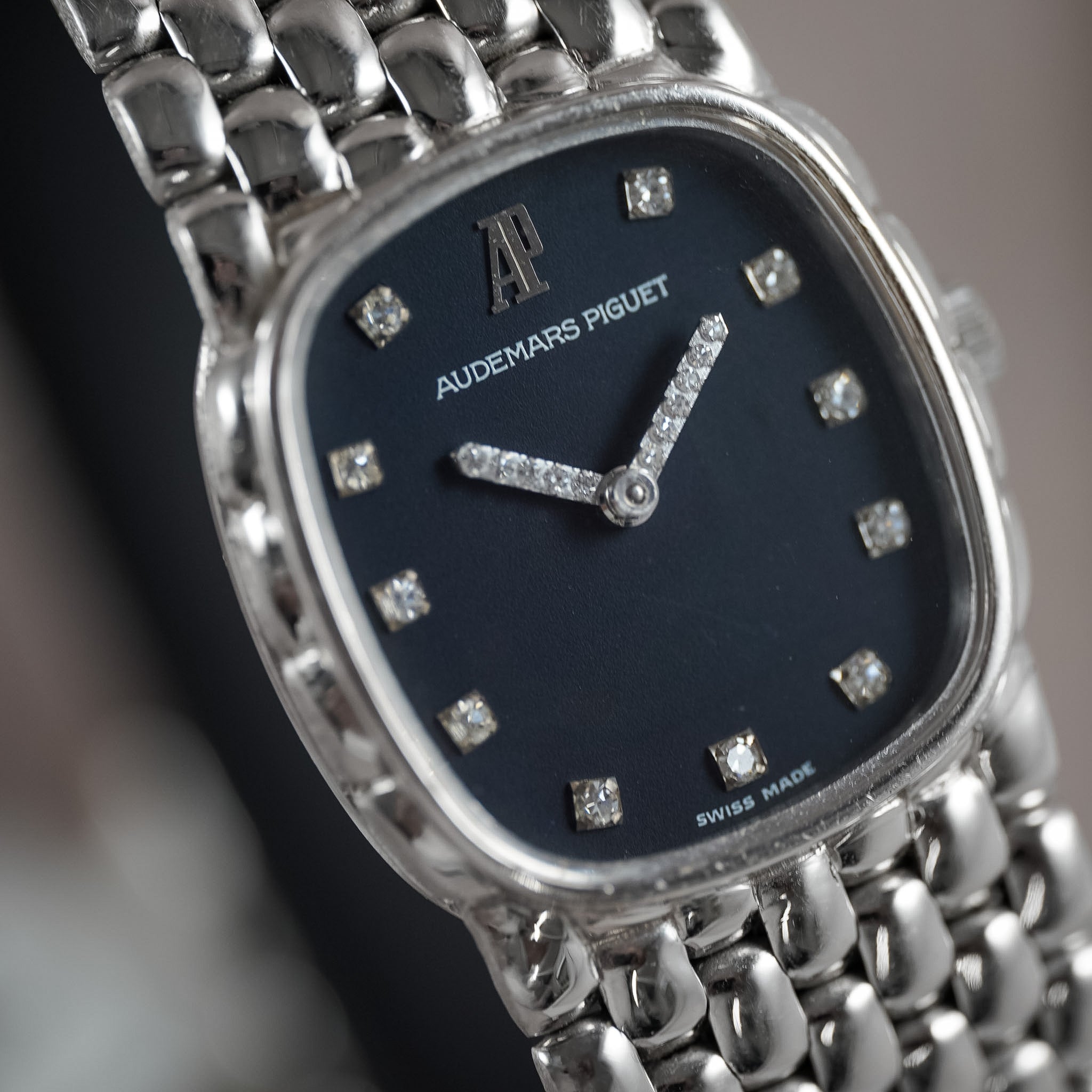 Close-up of an Audemars Piguet watch with a silver-toned metal bracelet and a dark blue dial accented with diamond hour markers and hands.