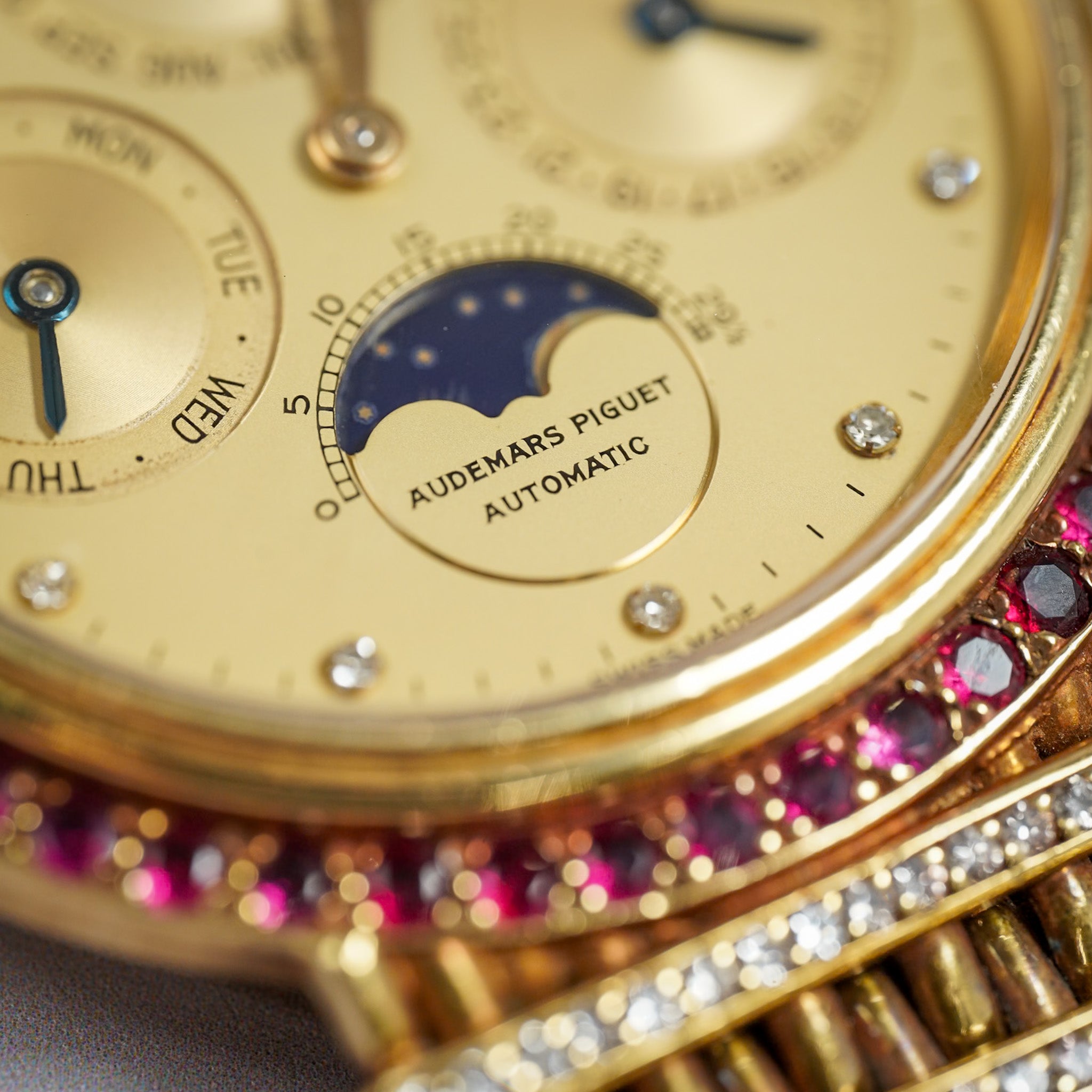 Closeup shot of a bejeweled Audemars Piguet perpetual calendar wristwatch with a ruby bezel and diamond hour markers