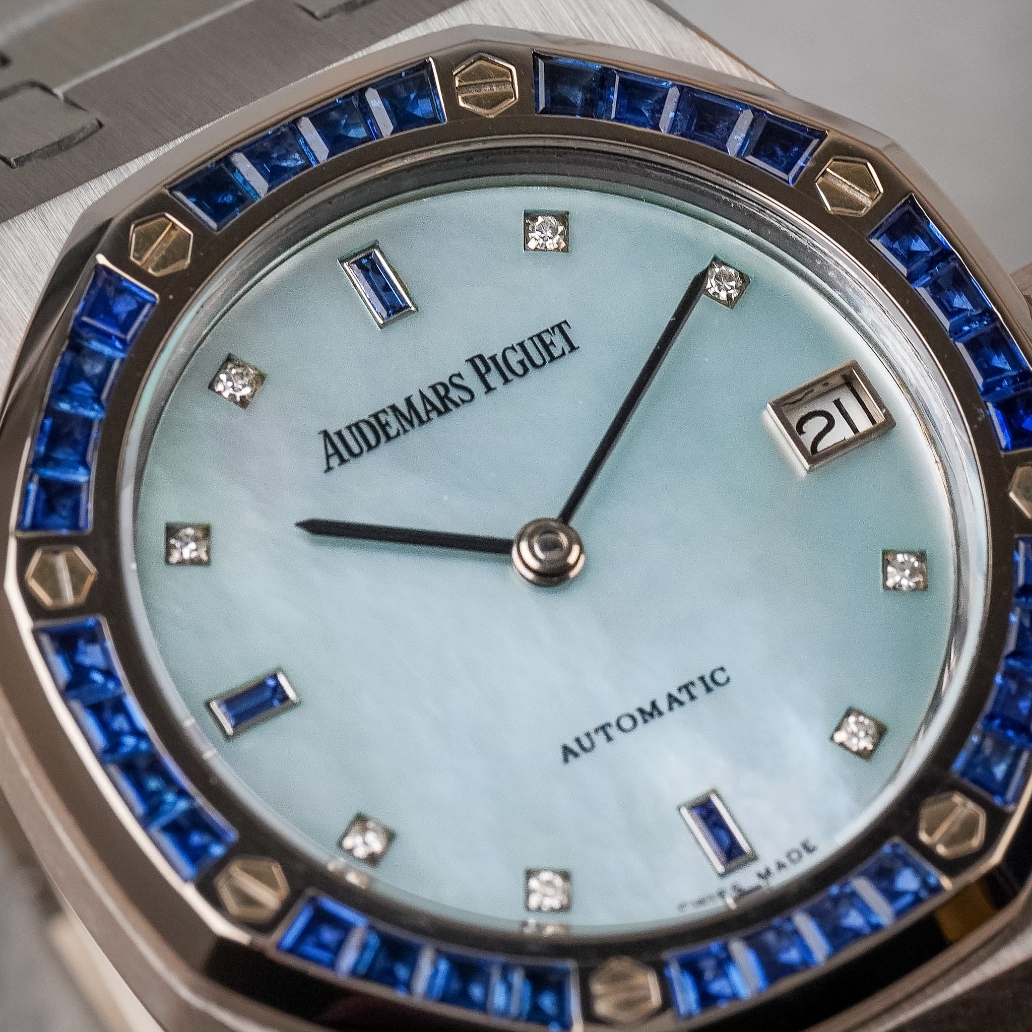 Closeup of a white gold Audemars Piguet Royal Oak with a blue sapphire octagonal bezel, a blue mother of pearl dial, and blue sapphire and diamond hour markers.