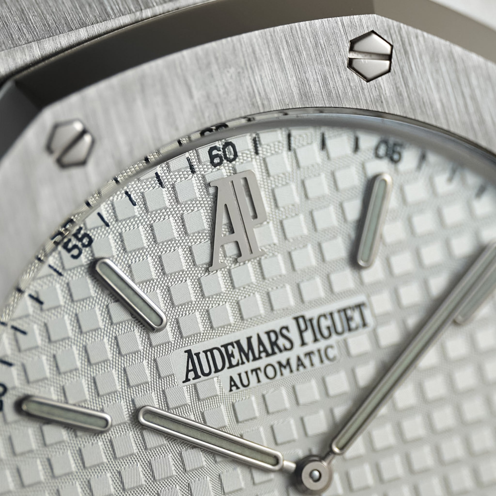 Close-up of an Audemars Piguet Automatic watch dial with a textured silver pattern, silver hour markers, and the brand name 'AUDEMARS PIGUET' visible on the face.