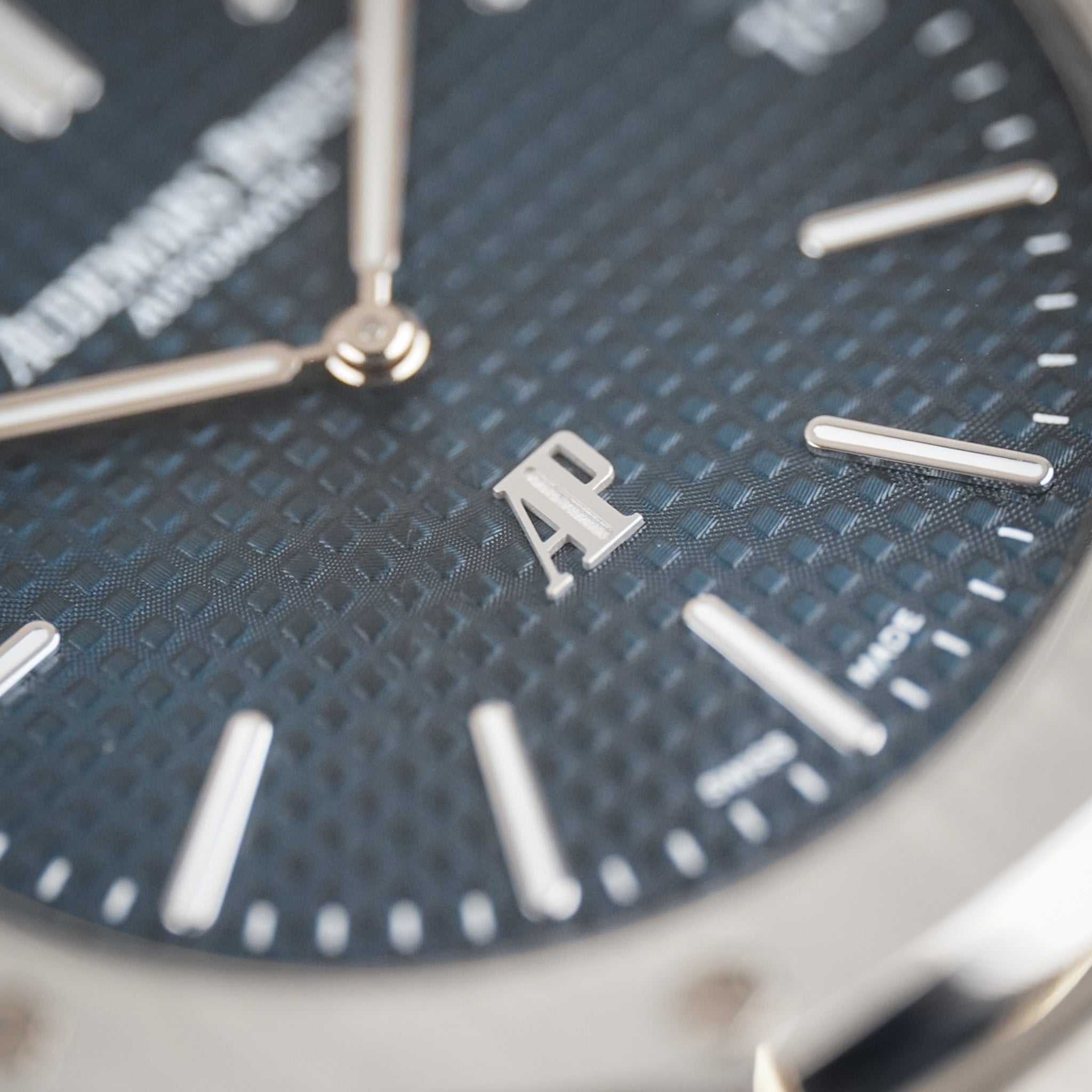 Closeup of a steel Audemars Piguet Royal Oak with a textured blue dial, silver hands and hour markers, and the AP logo at 6 o'clock