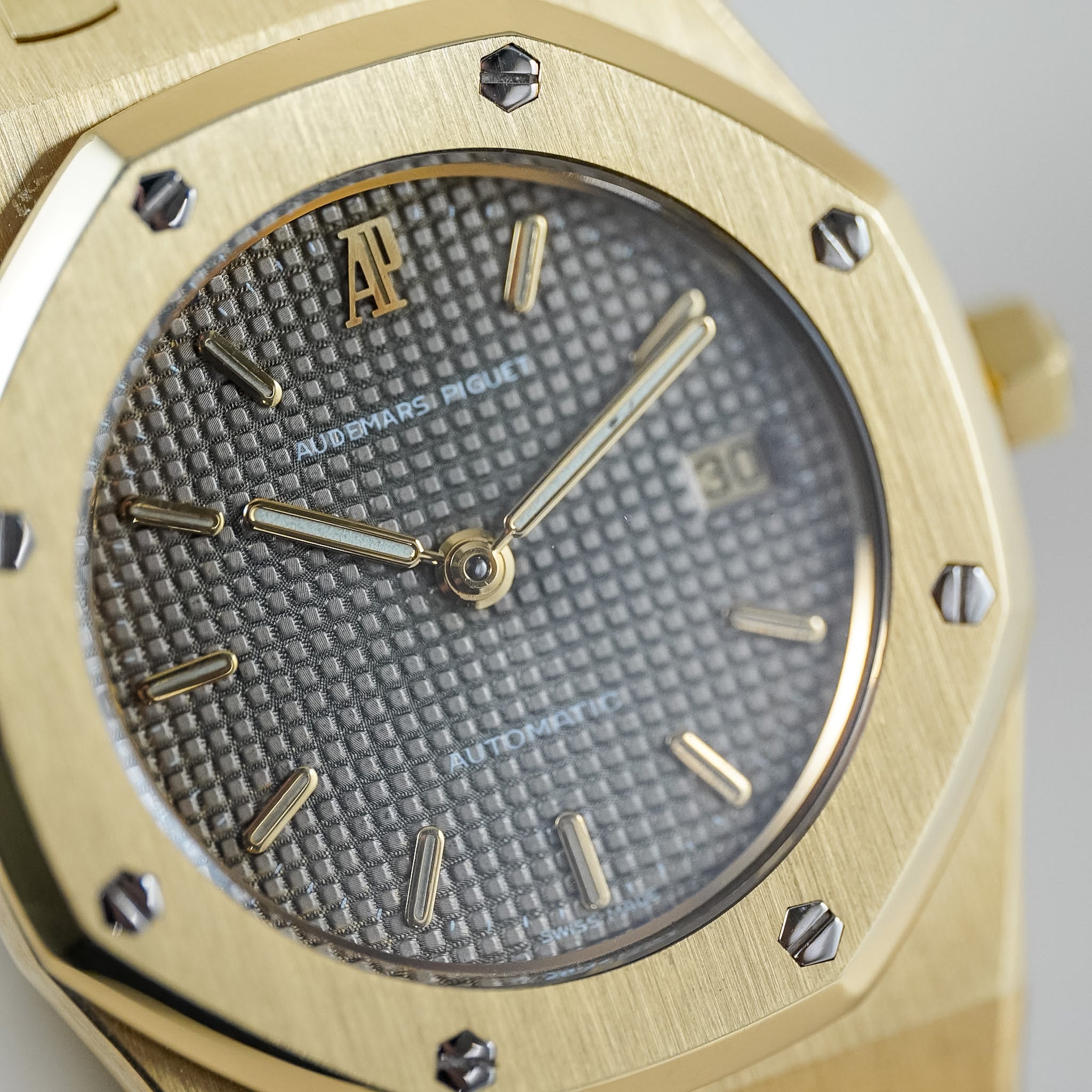 Close up of a yellow gold Audemars Piguet Royal Oak with a textured grey dial and a date window showing "30"