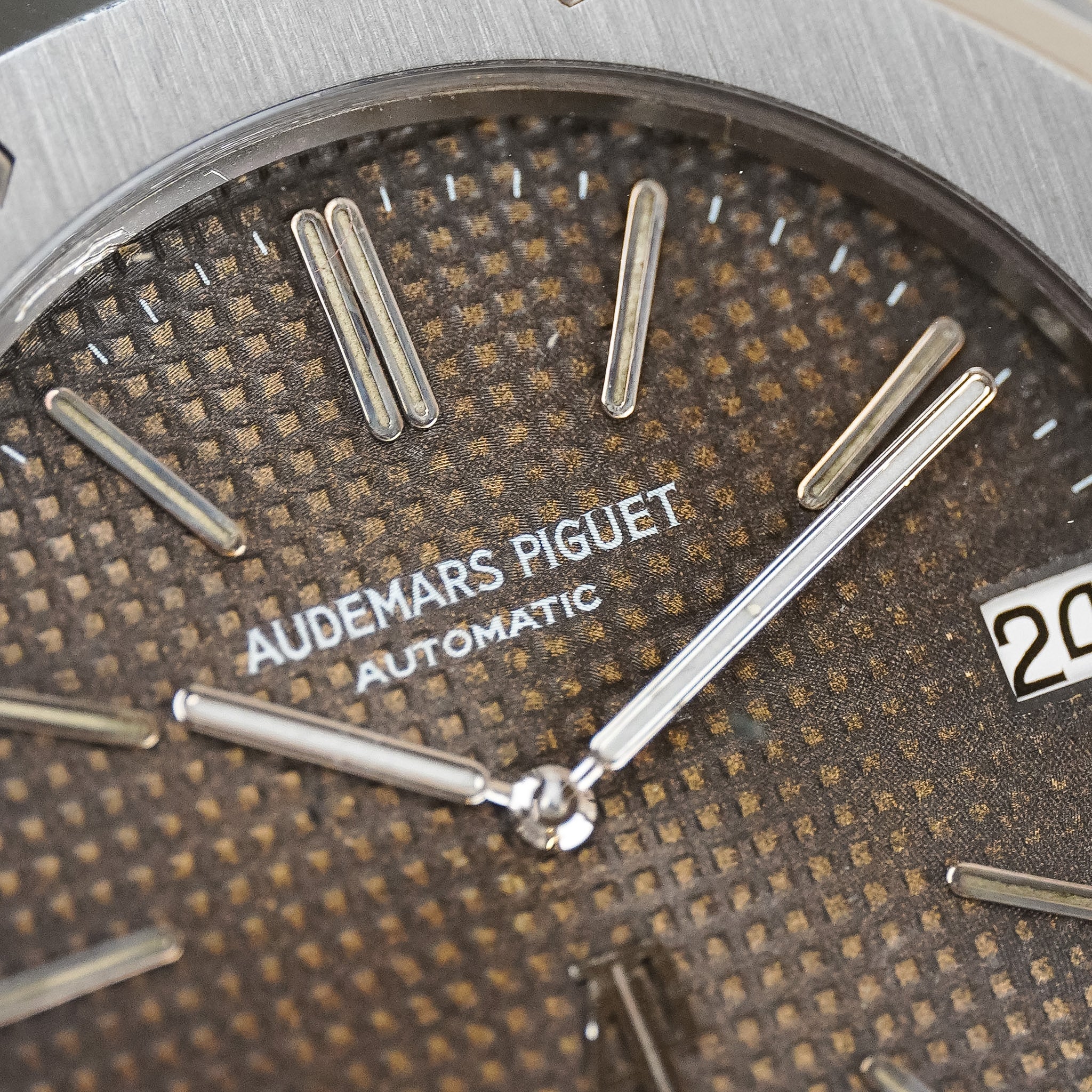 Closeup of an Audemars Piguet Royal Oak in steel with a textured tropical brown dial, silver hands and hour markers, and text saying "Audemars Piguet Automatic"