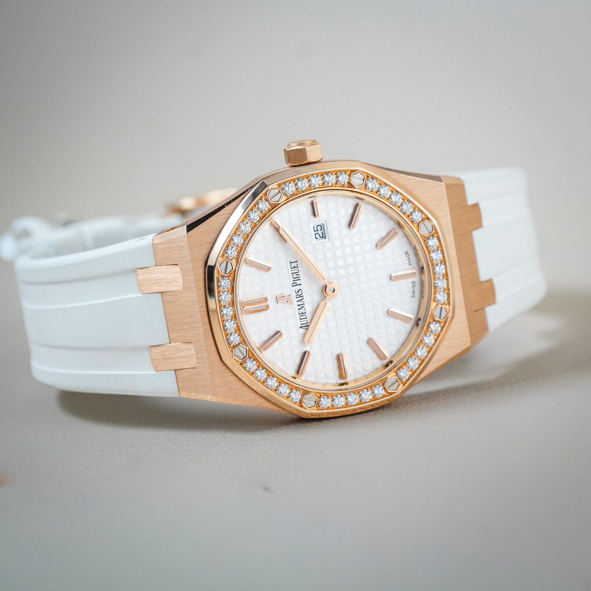 Audemars Piguet Royal Oak watch featuring a white rubber strap, white dial with diamond accents, and a rose gold case.