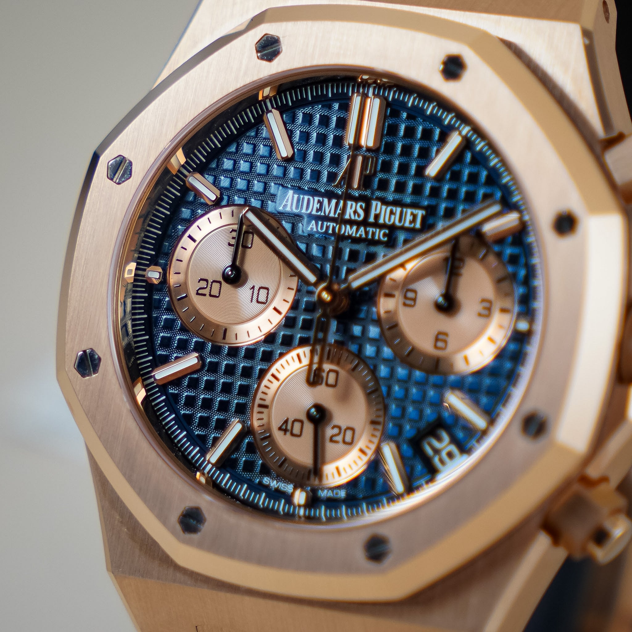 Close-up of an Audemars Piguet Royal Oak Automatic watch with a textured blue dial and rose gold-toned case.